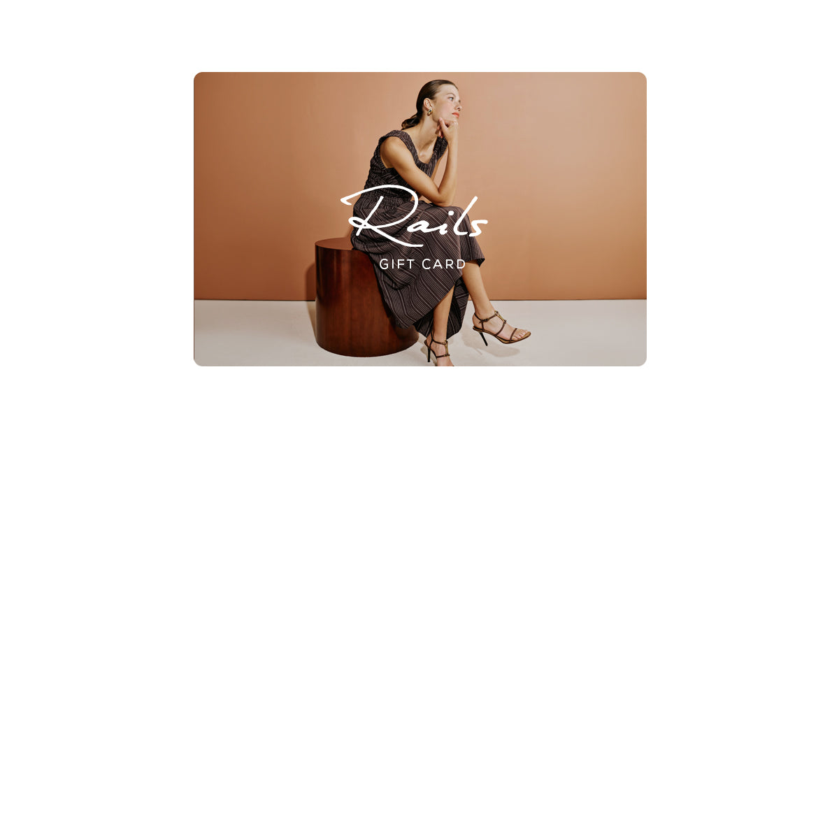 A rectangular Rail gift card centered on a white background. The card artwork shows a woman seated on a dark wooden stool against a warm tan wall, wearing a sleeveless dark dress and heeled sandals.