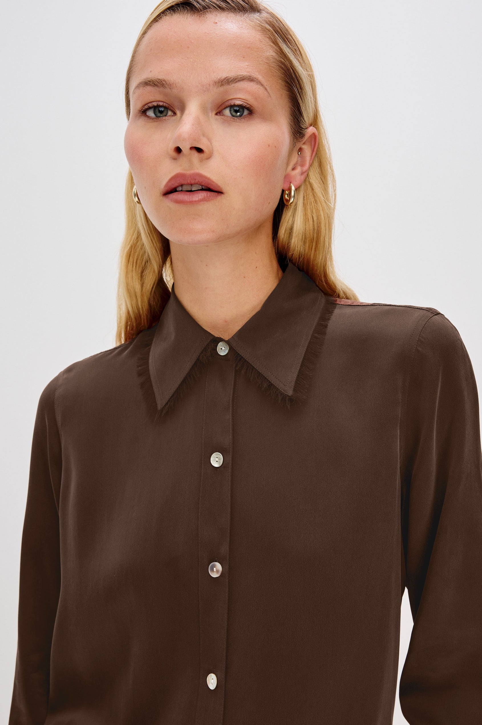 The Abbey is a silk charmeuse button-down shirt with raw edge detailing at the collar and cuffs, with a relaxed fit in Espresso Colorway - Close up of Details on Model