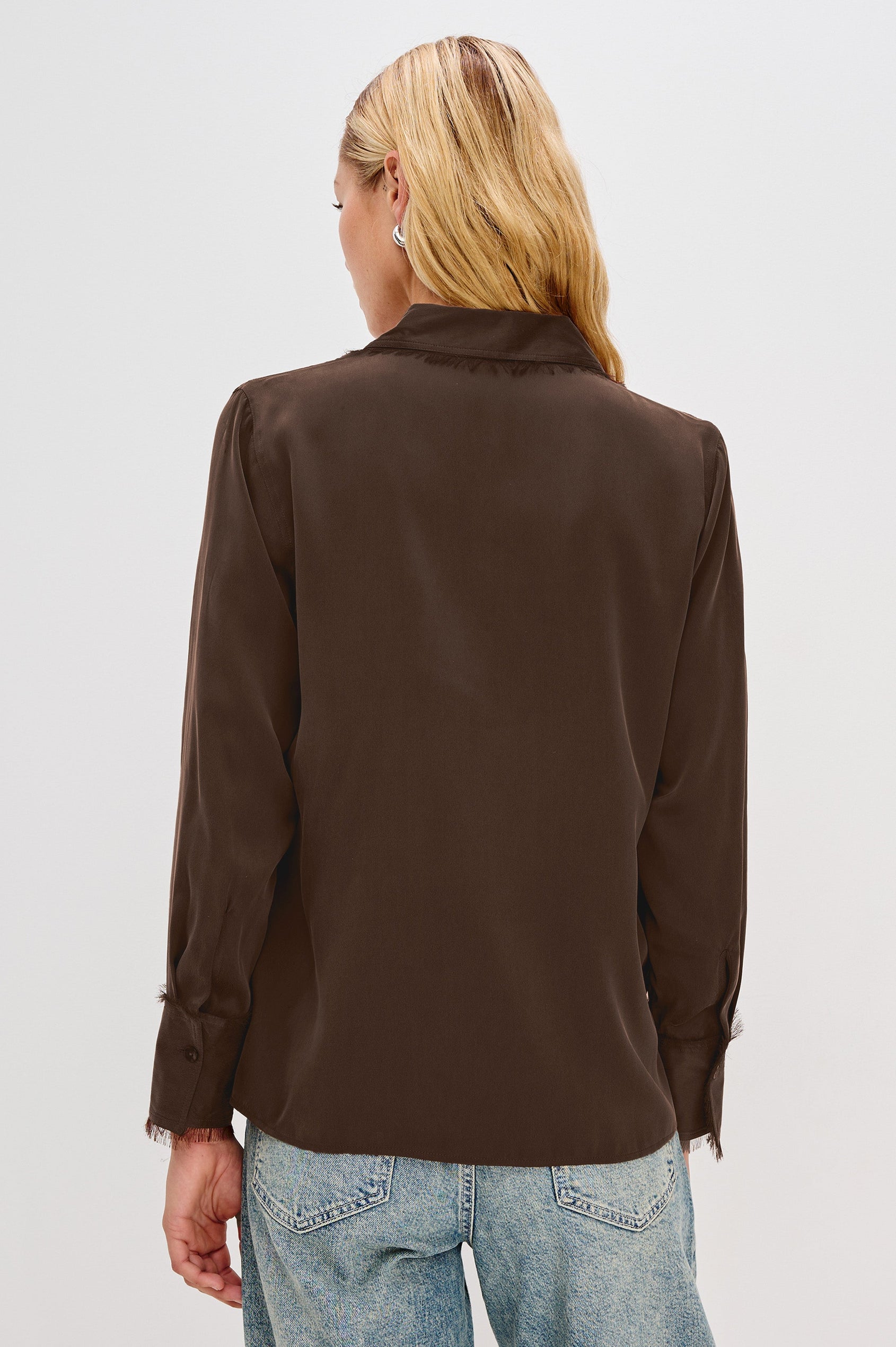 The Abbey is a silk charmeuse button-down shirt with raw edge detailing at the collar and cuffs, with a relaxed fit in Espresso Colorway - Back View Featured on Model