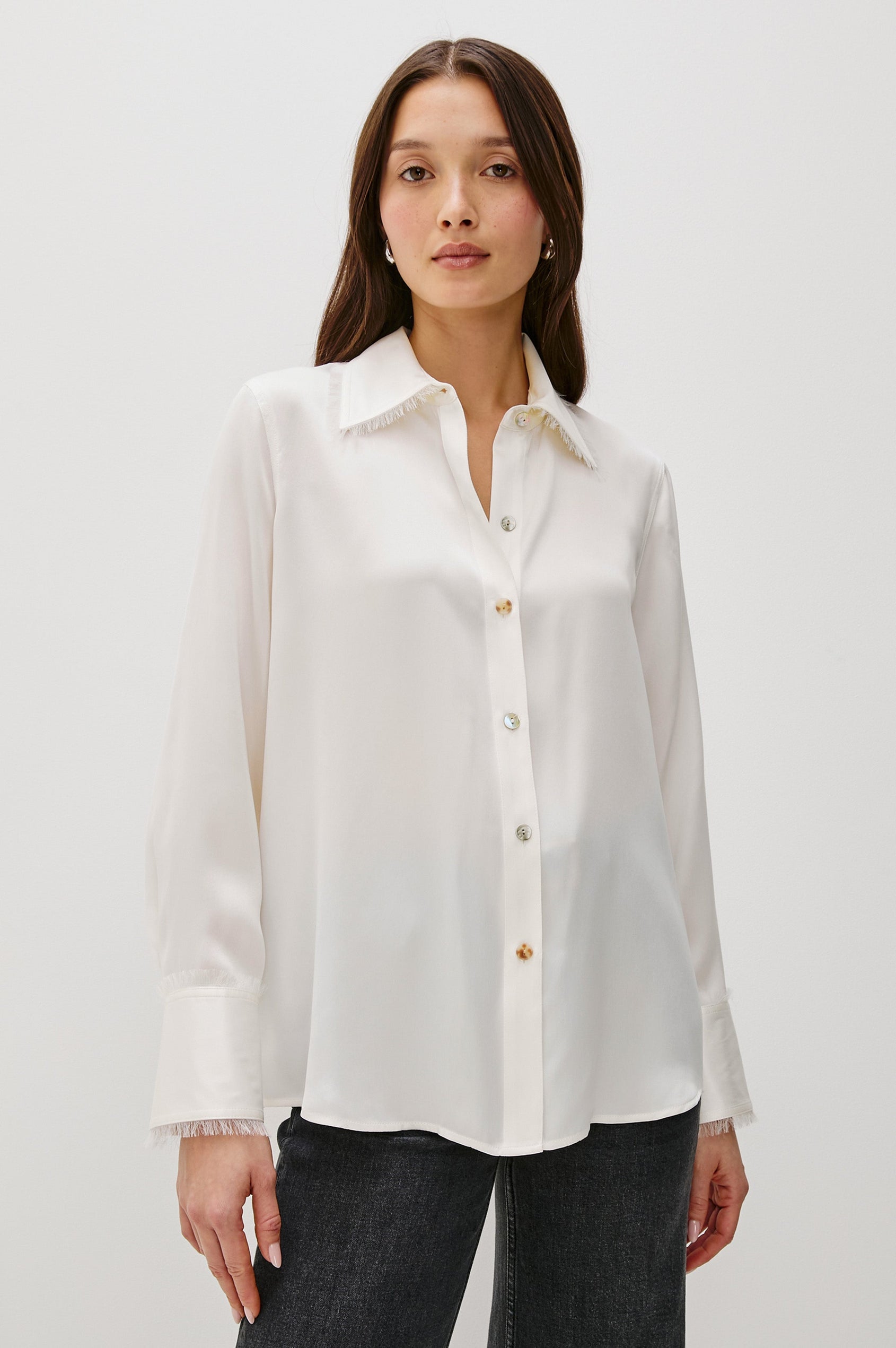 The Abbey is a silk charmeuse button-down shirt with raw edge detailing at the collar and cuffs, with a relaxed fit in Ivory Colorway - Front View Featured on Model, Untucked