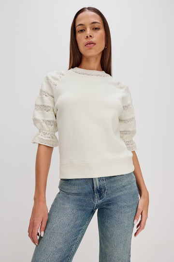 The Aggy is a raglan sleeve crew neck knit top, the sleeves are elbow length with an elastic lace cuff, there is lace inserts on sleeves and neck opening with a ribbed hem in Ivory colorway. Front View Featured on Model.