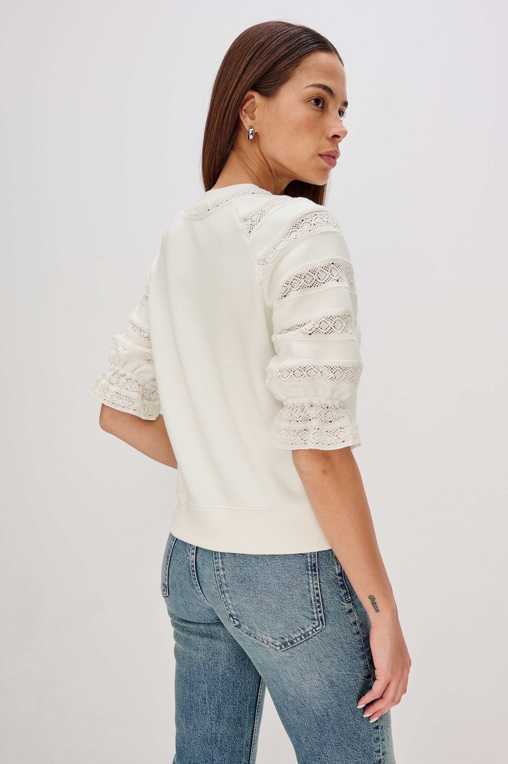 The Aggy is a raglan sleeve crew neck knit top, the sleeves are elbow length with an elastic lace cuff, there is lace inserts on sleeves and neck opening with a ribbed hem in Ivory colorway. Back View Featured on Model.