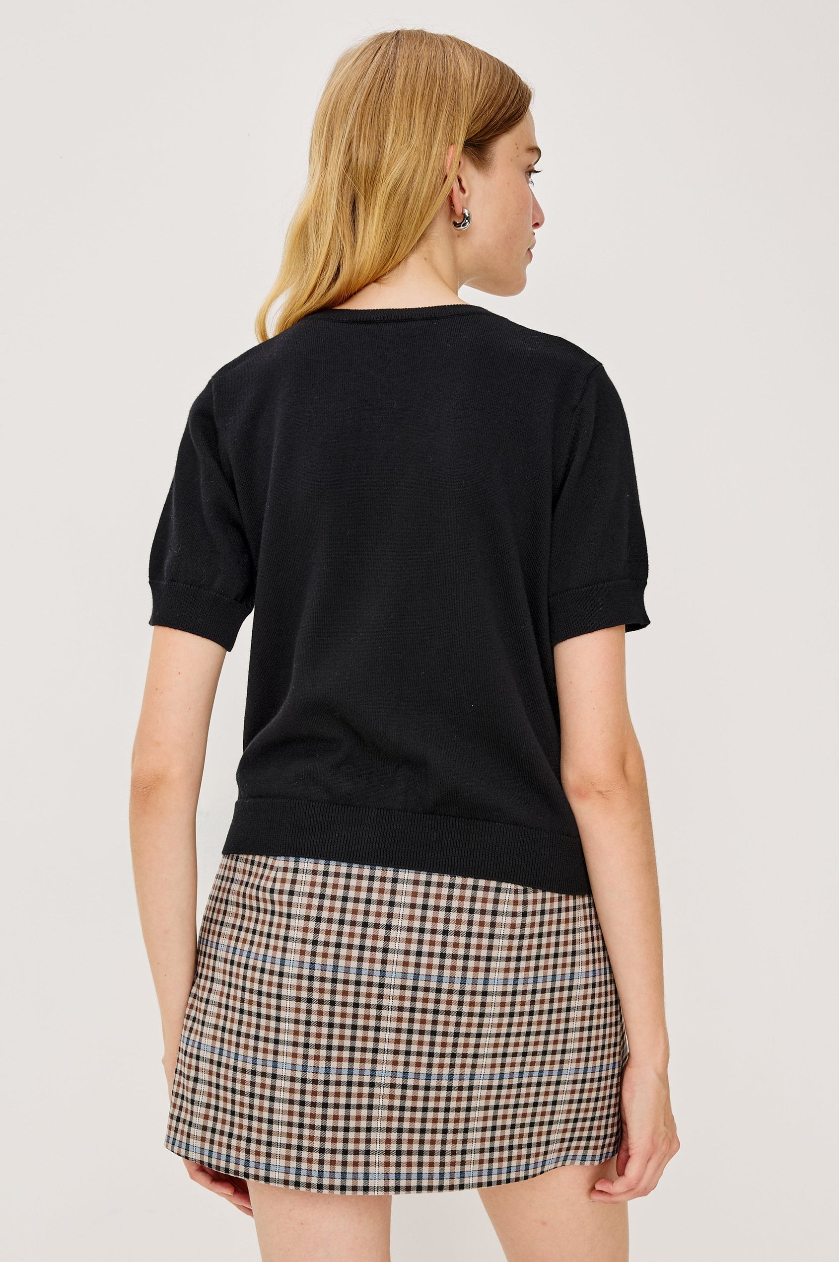 Aisley, a short-sleeve cotton-cashmere sweater with a semi-fitted silhouette. The sweater features a round neckline and is accented with a row of elegant pearl buttons down the front. Back View on Model