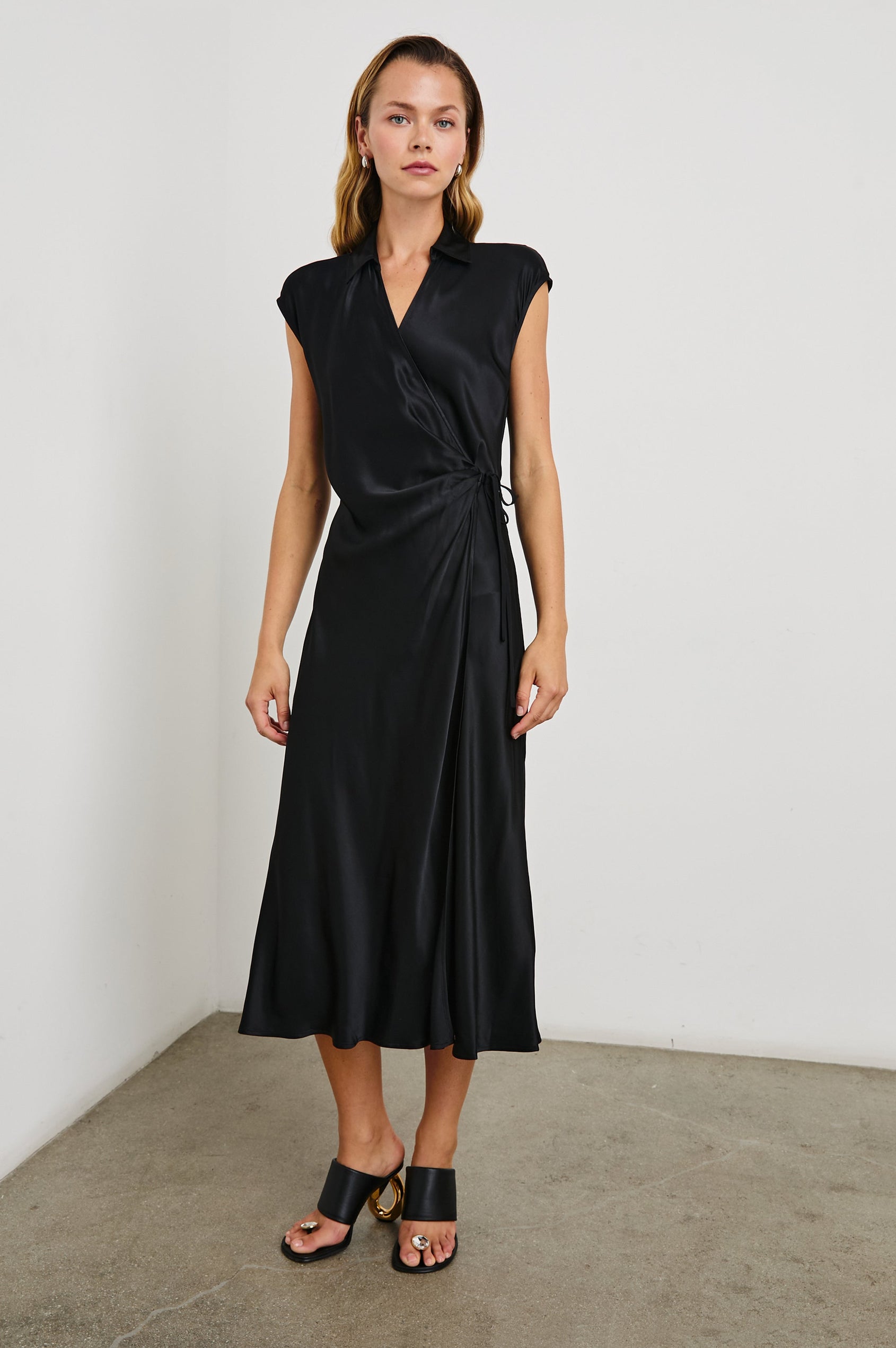 Alai Short Sleeve Midi Wrap Dress with Cap Sleeves, a Collar and a Side Tie in Black Colorway - Front Full Body View Featured on Model 