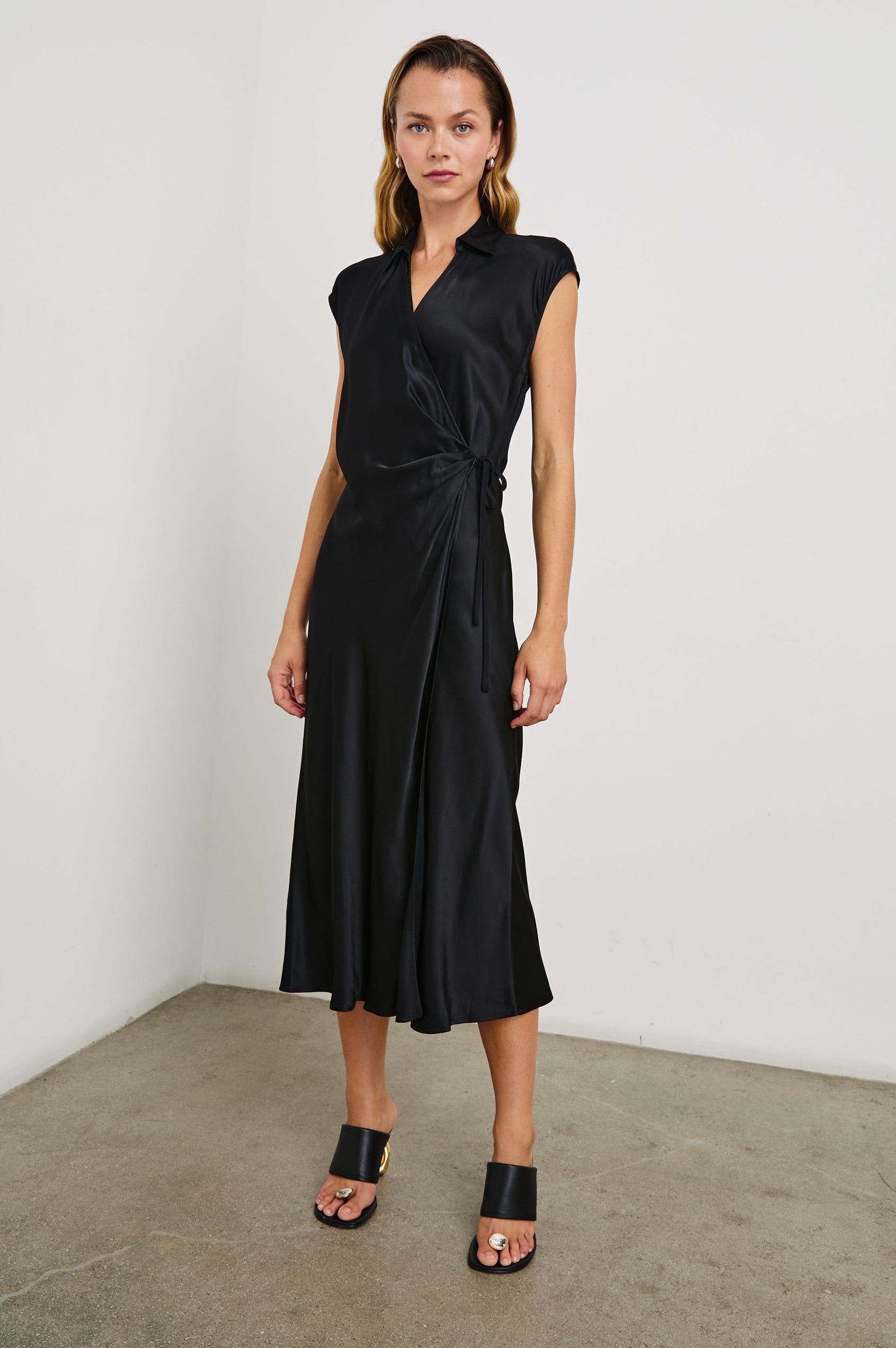Alai Short Sleeve Midi Wrap Dress with Cap Sleeves, a Collar and a Side Tie in Black Colorway - Front Full Body View Featured on Model 