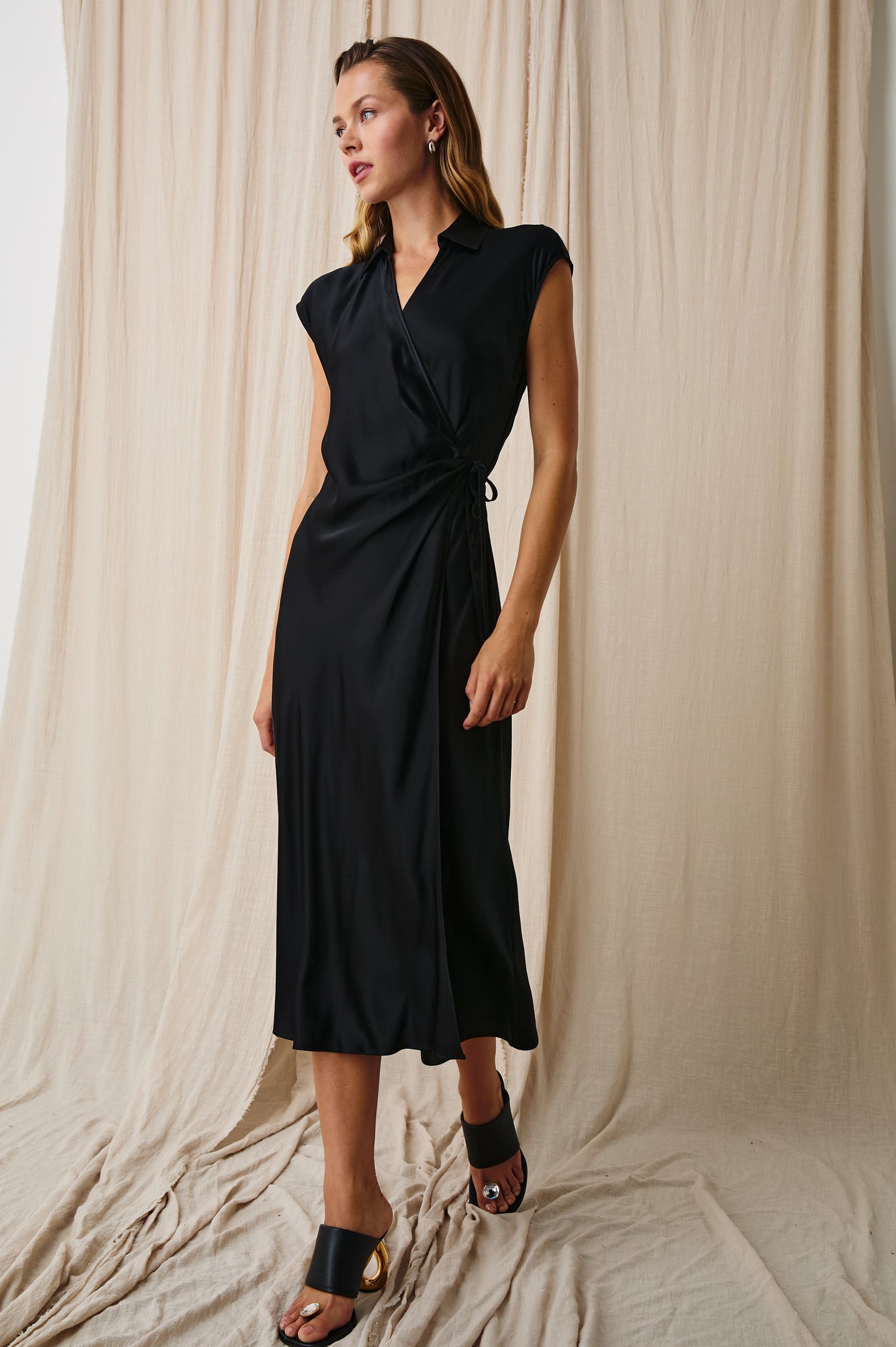 Alai Short Sleeve Midi Wrap Dress with Cap Sleeves, a Collar and a Side Tie in Black Colorway - Front Full Body View Featured on Model 