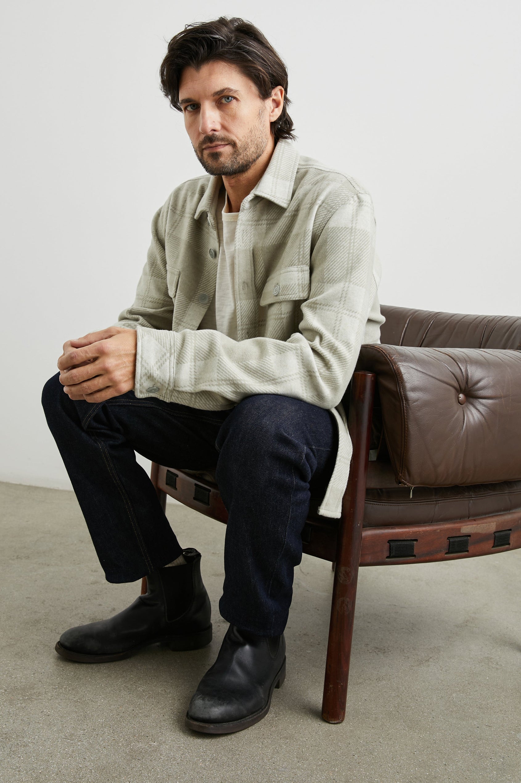 Alder Long-Sleeve Button up with Two Buttoned Chest Flap Pockets in Fawn Cream Colorway, a plaid - Front Unbuttoned Full Body View Featured on Seated Model