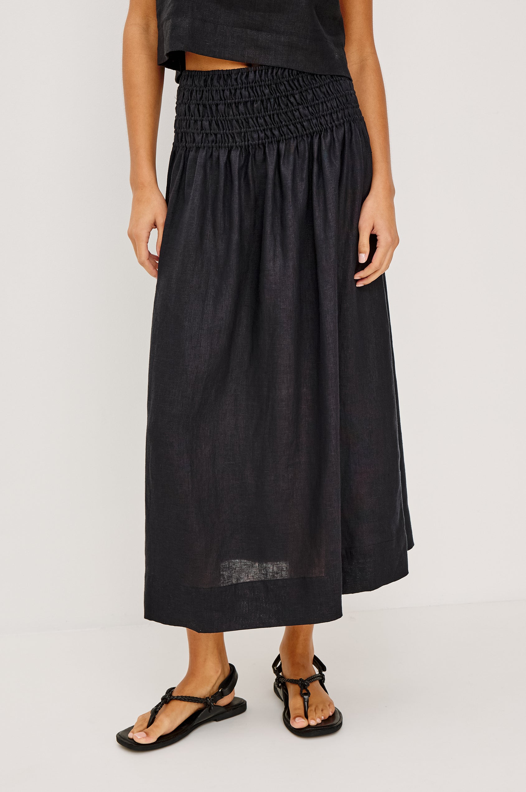 Alessa Midi Skirt in Heavy Linen With Wide Smocked Waistband and A-Line Silhouette in Black Linen Colorway - Lower Body Front View Featured on Model