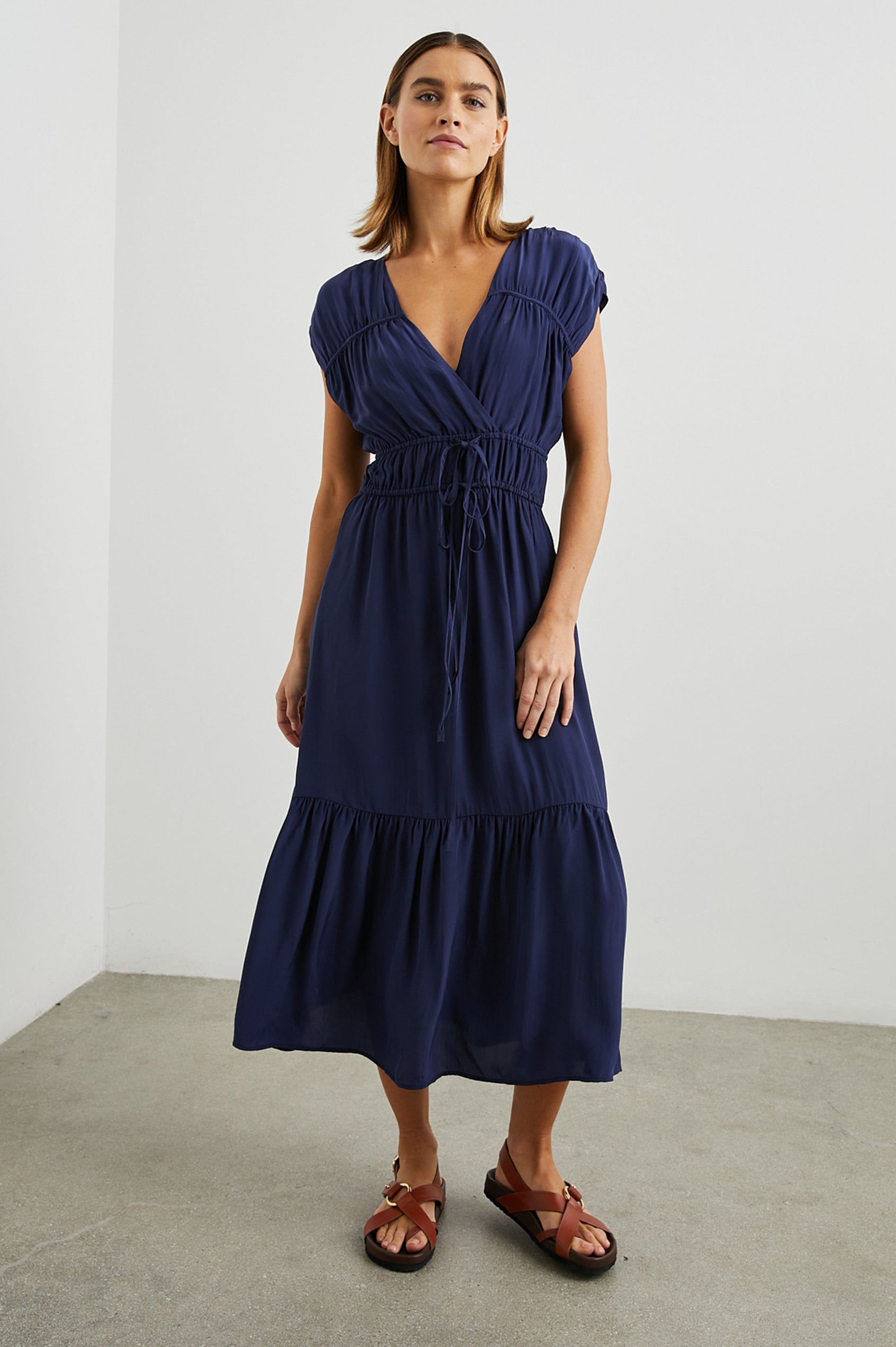 Aletta Short Sleeve Midi Dress with Cap Sleeves with Wide Arm Holes, Two Drawstrings at the Waist, a Deep V Neck, a Tiered Skirt and Ruching at the Front Yoke Seam and Shoulder Seam in Admiral Blue Colorway - Front Full Body View Featured on Model 