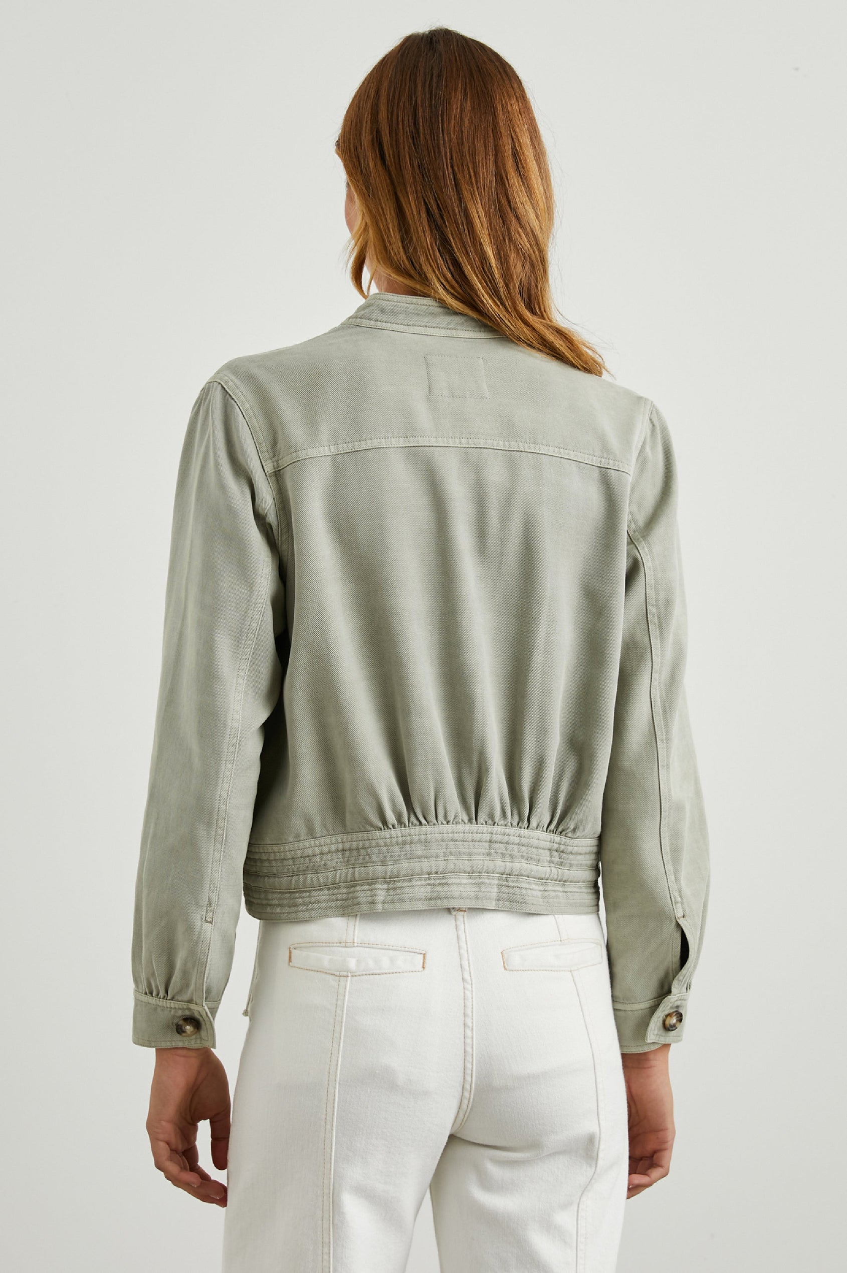 Alma Jacket with Button Closure, Mandarin Collar, Two Large Chest Button Patch Pockets and a Drawcord at the Hem in Sage Colorway - Back View Featured on Model