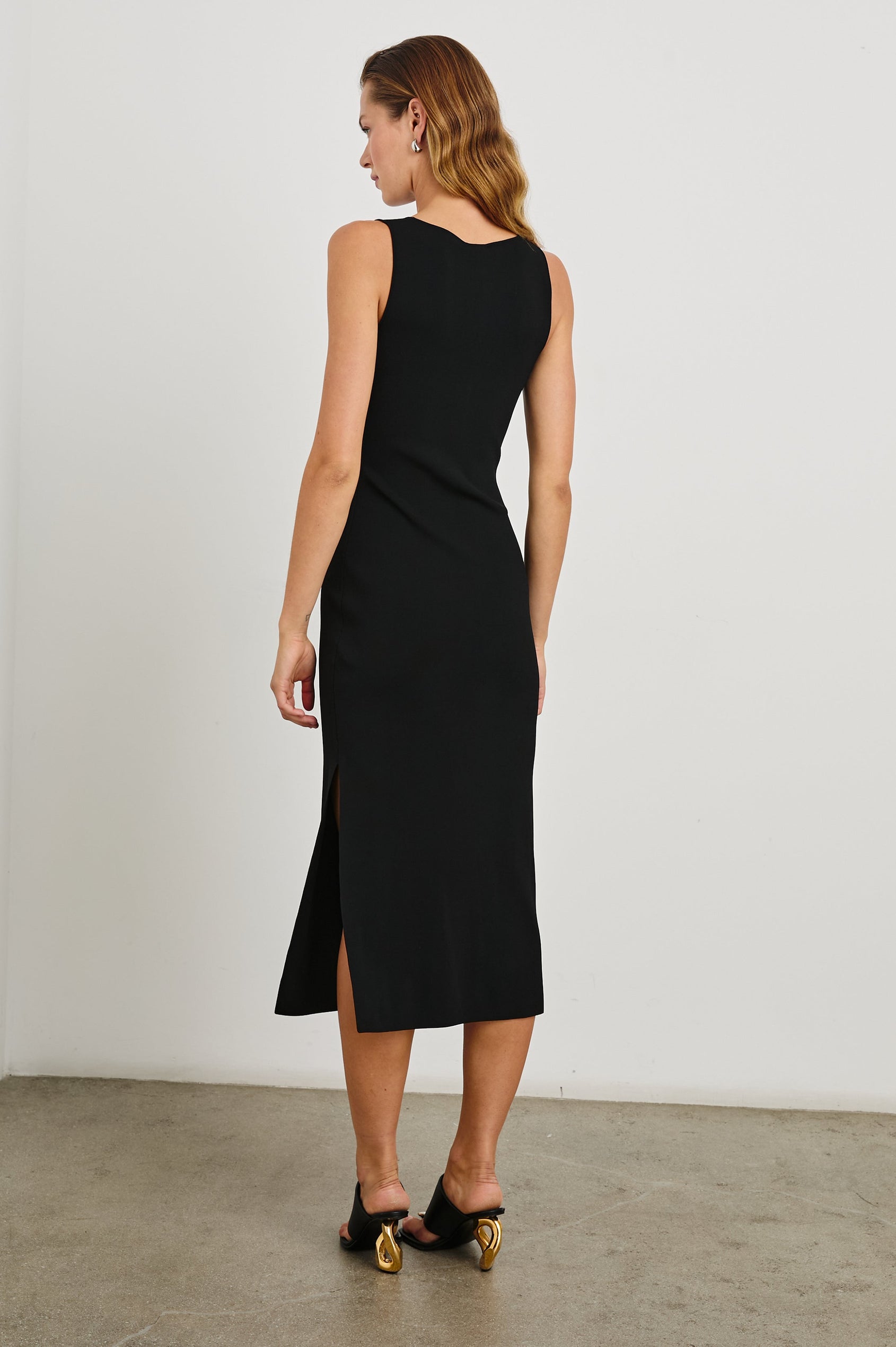 Alora Sleeveless Midi Dress with a Shallow Boat Neck, Mid-Thigh Side Slit, and a Fine Rib Knit in Black Colorway - Back Full Body View Featured on Model