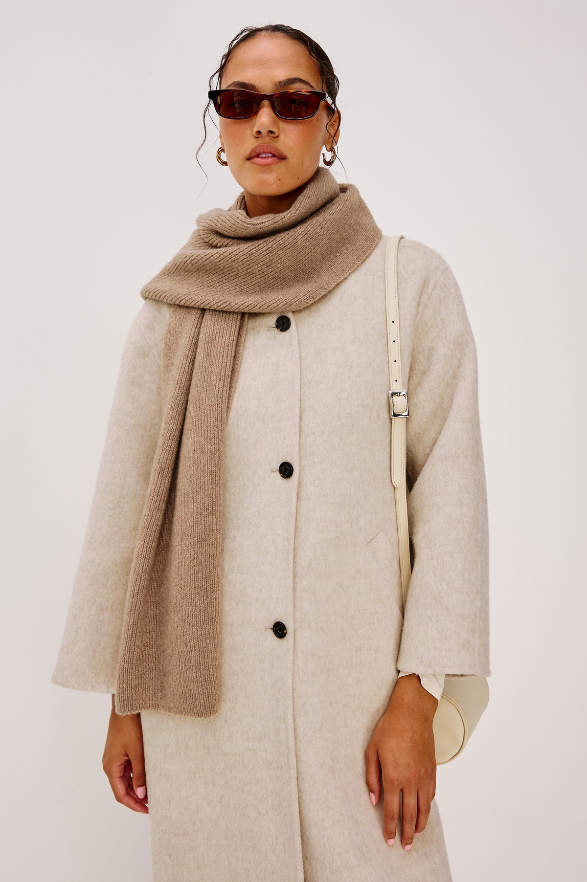 Alps is a cashmere scarf in Oat colorway. Front view featured on model.
