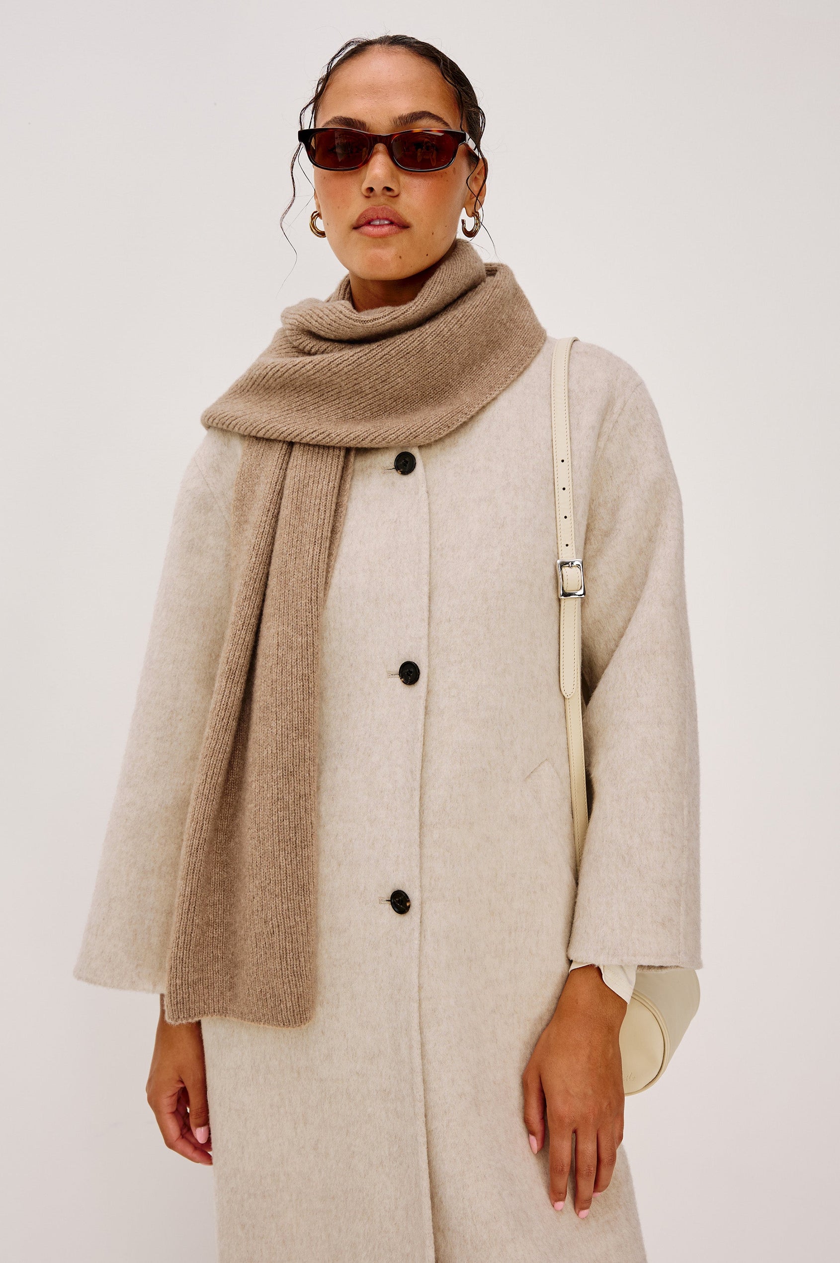 Alps is a cashmere scarf in Oat colorway. Front view featured on model.