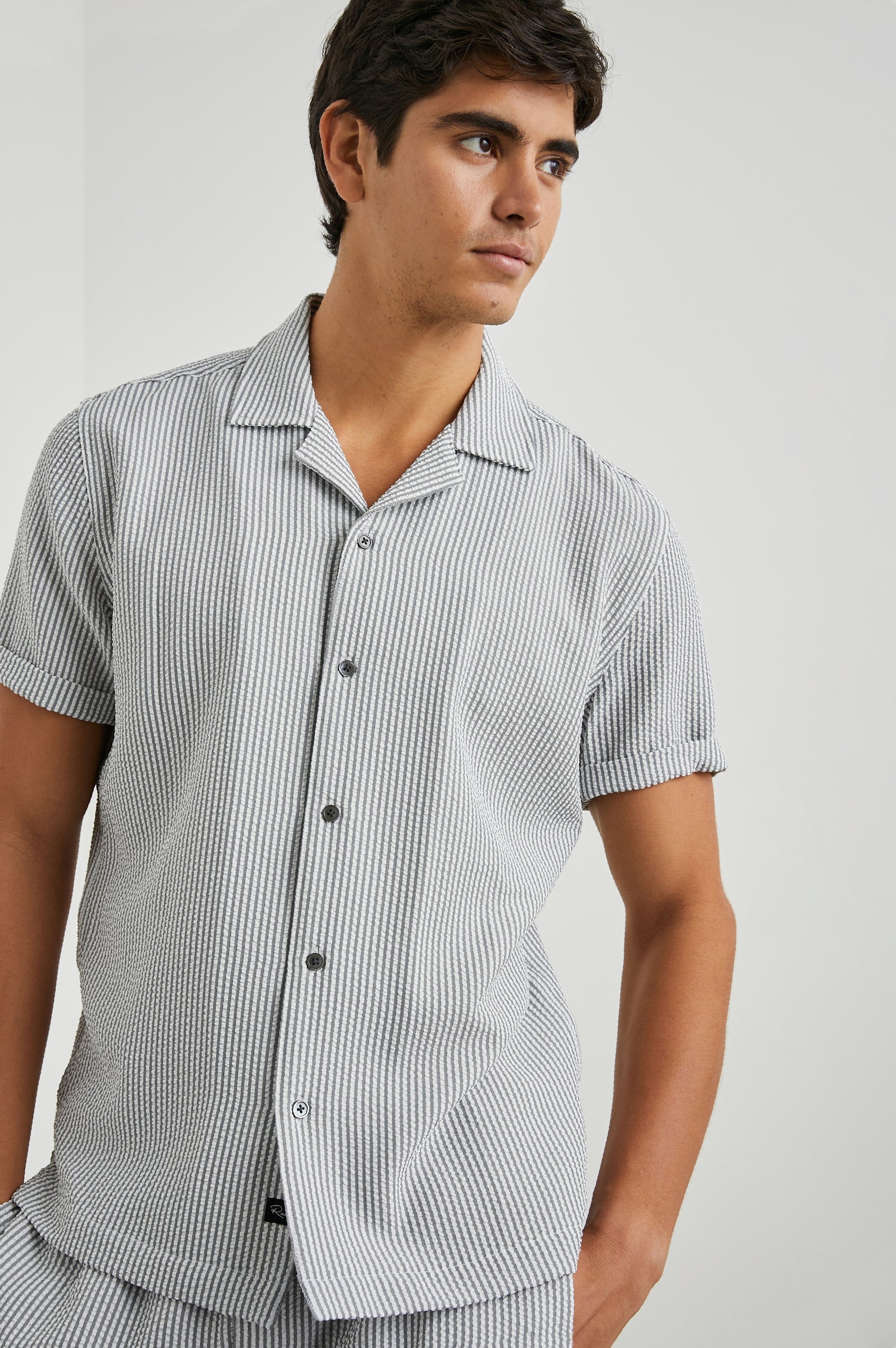 Amalfi Short-Sleeve Button Up in Faded Seersucker Colorway, Grey and white thin vertical stripes  - Front View Featured on Model