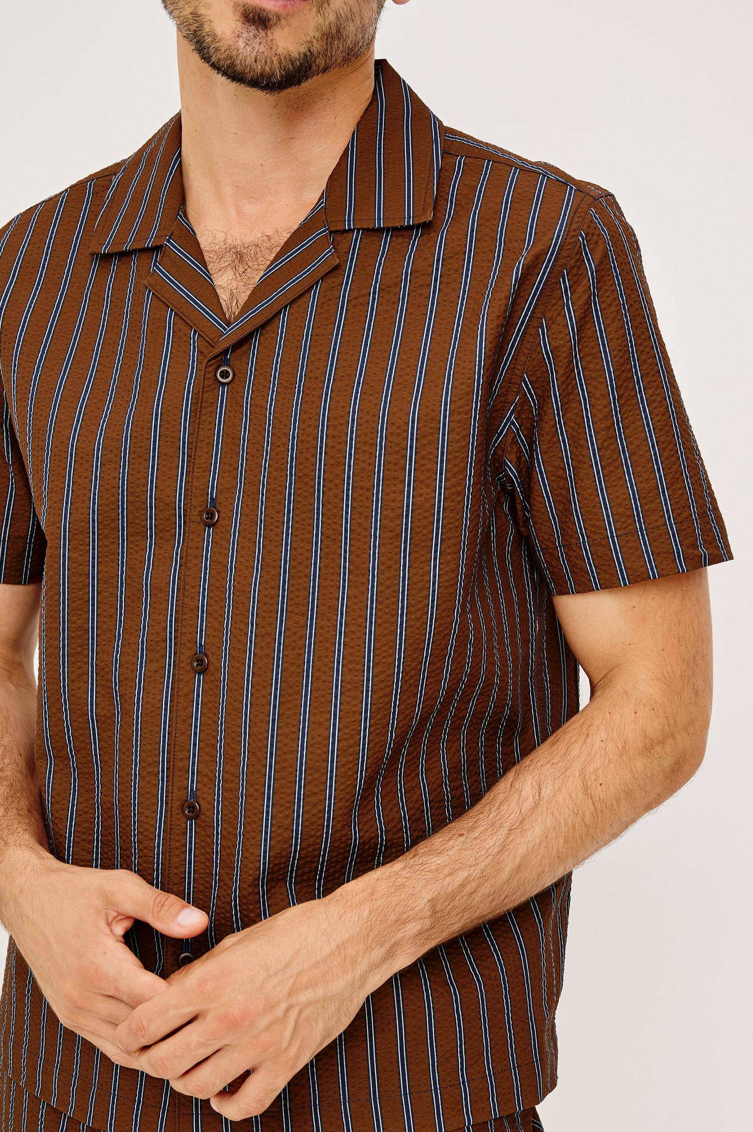 Amalfi Camp Shirt in Lightweight Seersucker With Notched Collar, Front Buttons, Short Sleeves, and Relaxed Fit in Rust Navy Stripe Colorway - Upper Body Front View Featured on Model