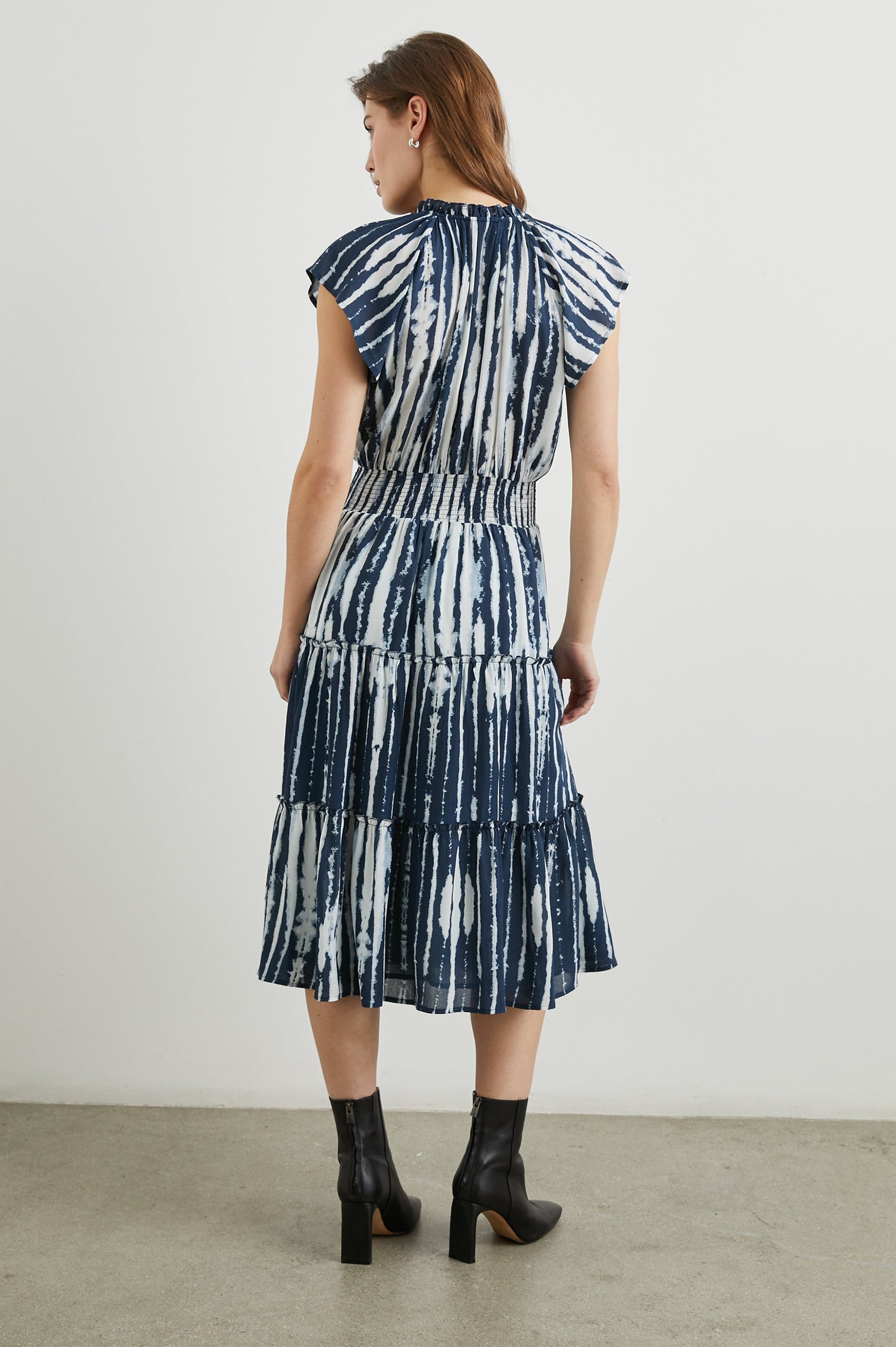 Amellia Short-Sleeve Midi Dress with Smocked Waist and Collar, V Neck, and a Tiered Skirt in Indigo Nile Stripe Colorway, White and Indigo Streaks - Back Full Body View Featured on Model