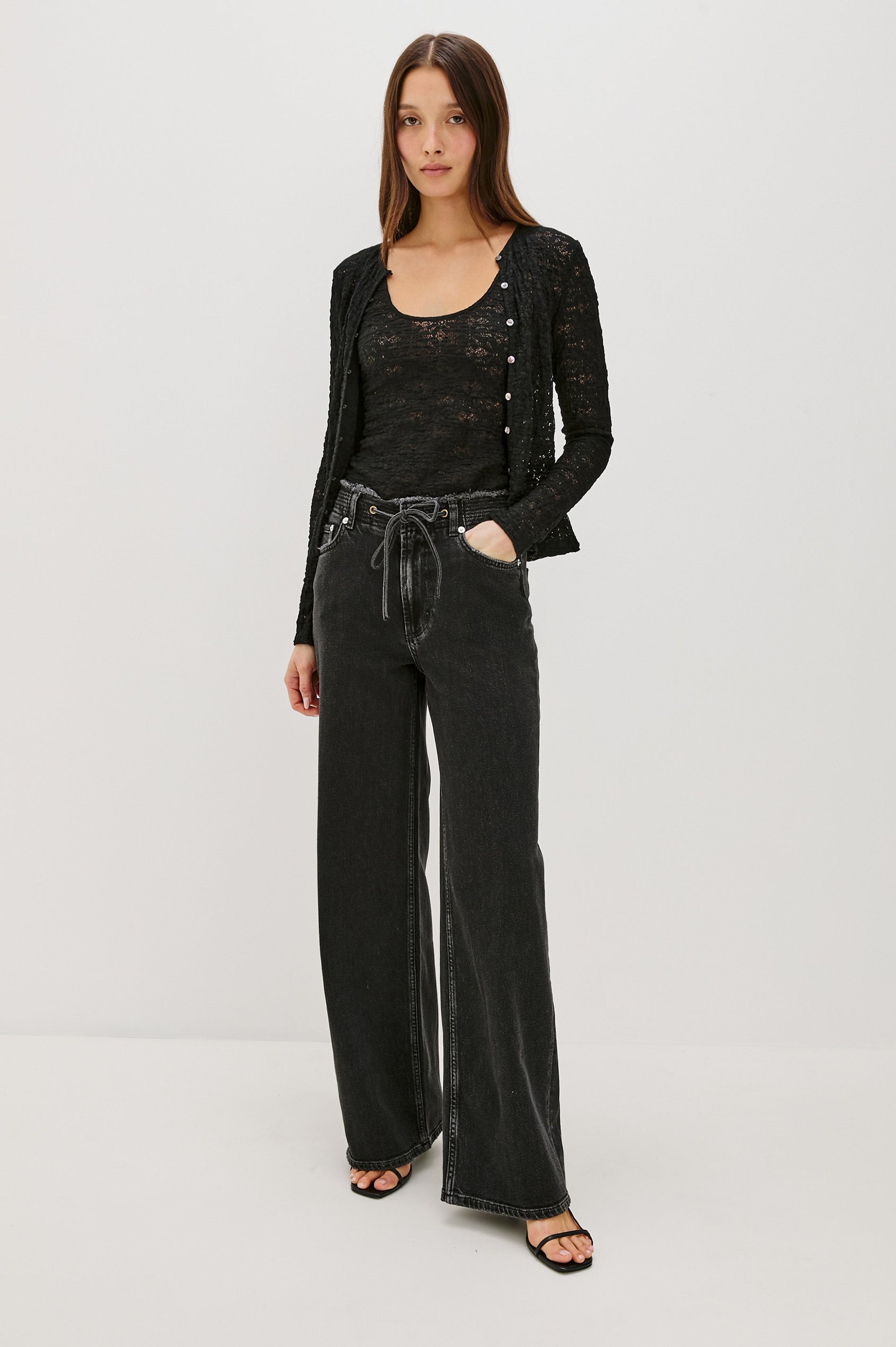 Angeleno mid rise slouchy wide leg jean with a drawstring waist tie, gromets and a raw edge waistband in a black wash Ash Black - front full body view featured on model.