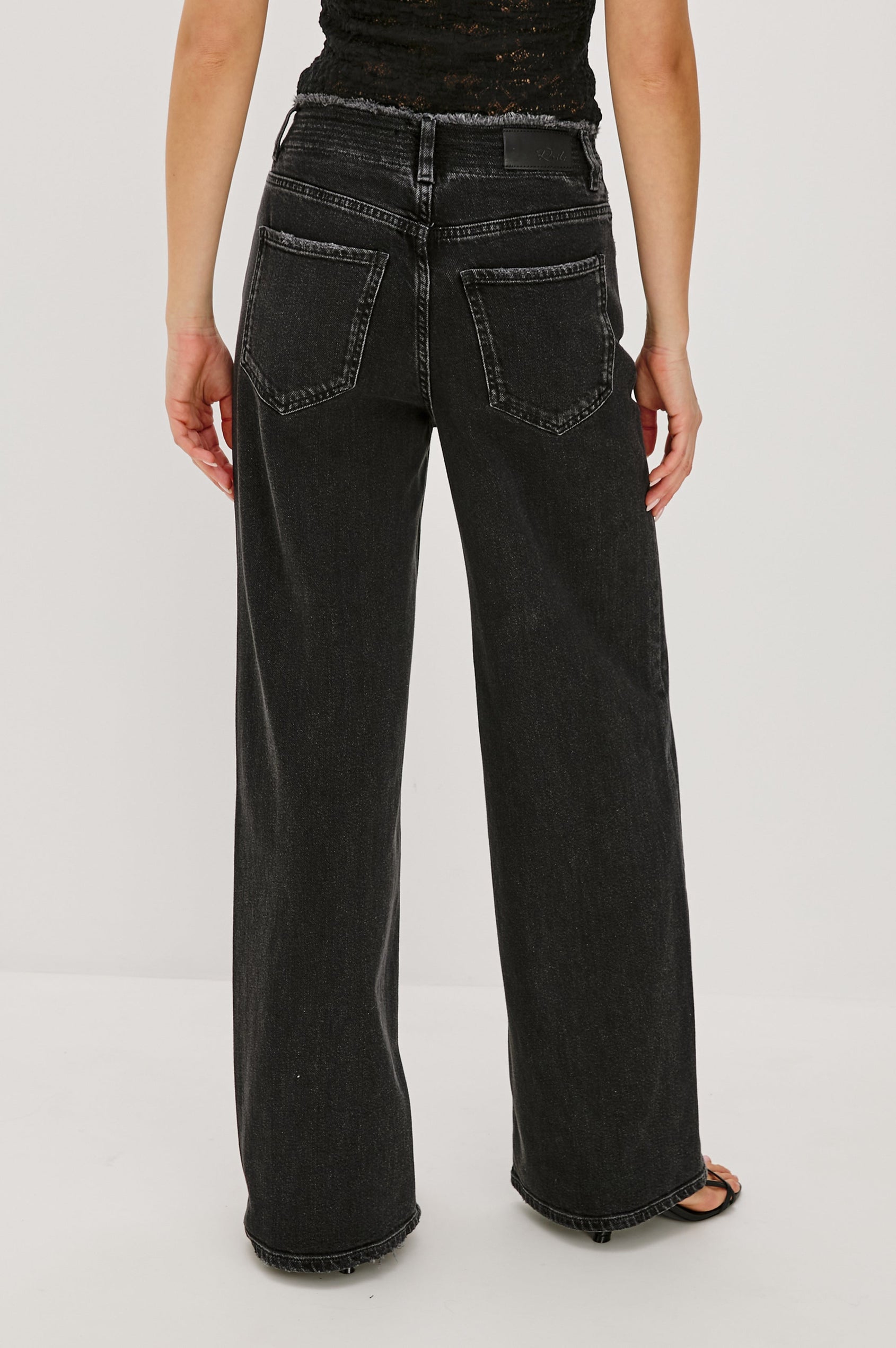 Angeleno mid rise slouchy wide leg jean with a drawstring waist tie, gromets and a raw edge waistband in a black wash Ash Black - back view featured on model.