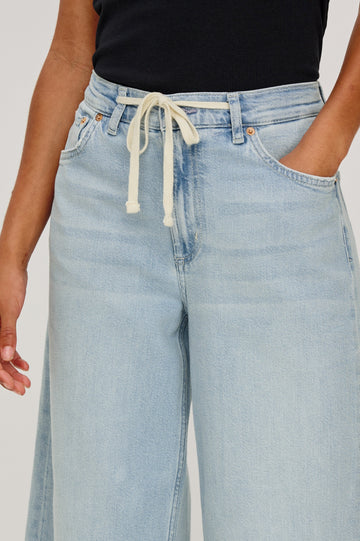 Angeleno Crop Denim Pant, Wide Leg, Five Pocket Zip Fly with a White Drawstring Tie at Waist in Light Wash Scuba Colorway. Front Detailed View Shown on Model.