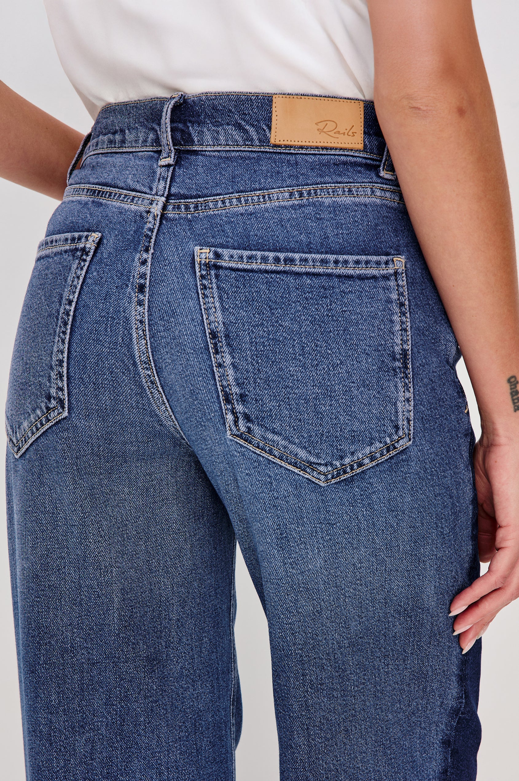 Angeleno is a mid rise 5-pocket, wide leg jean with a contrast godet in Indigo Grove colorway, a medium blue wash. Back detail view featured on model.