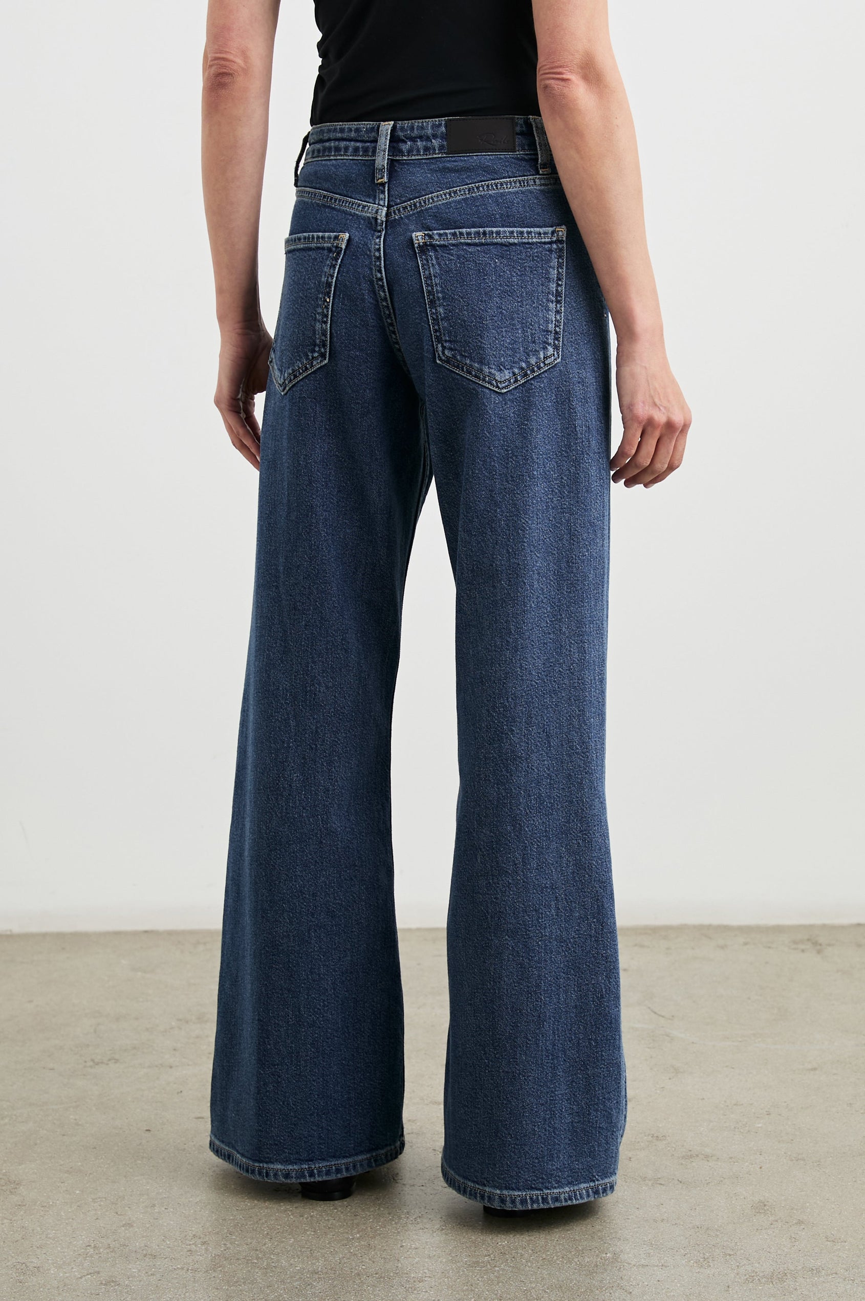 Angeleno Wide Leg Denim Pants with Belt Loops, Two Front Pockets and Two Back Patch Pockets in Pebble Blue Colorway - Back View Featured on Model
