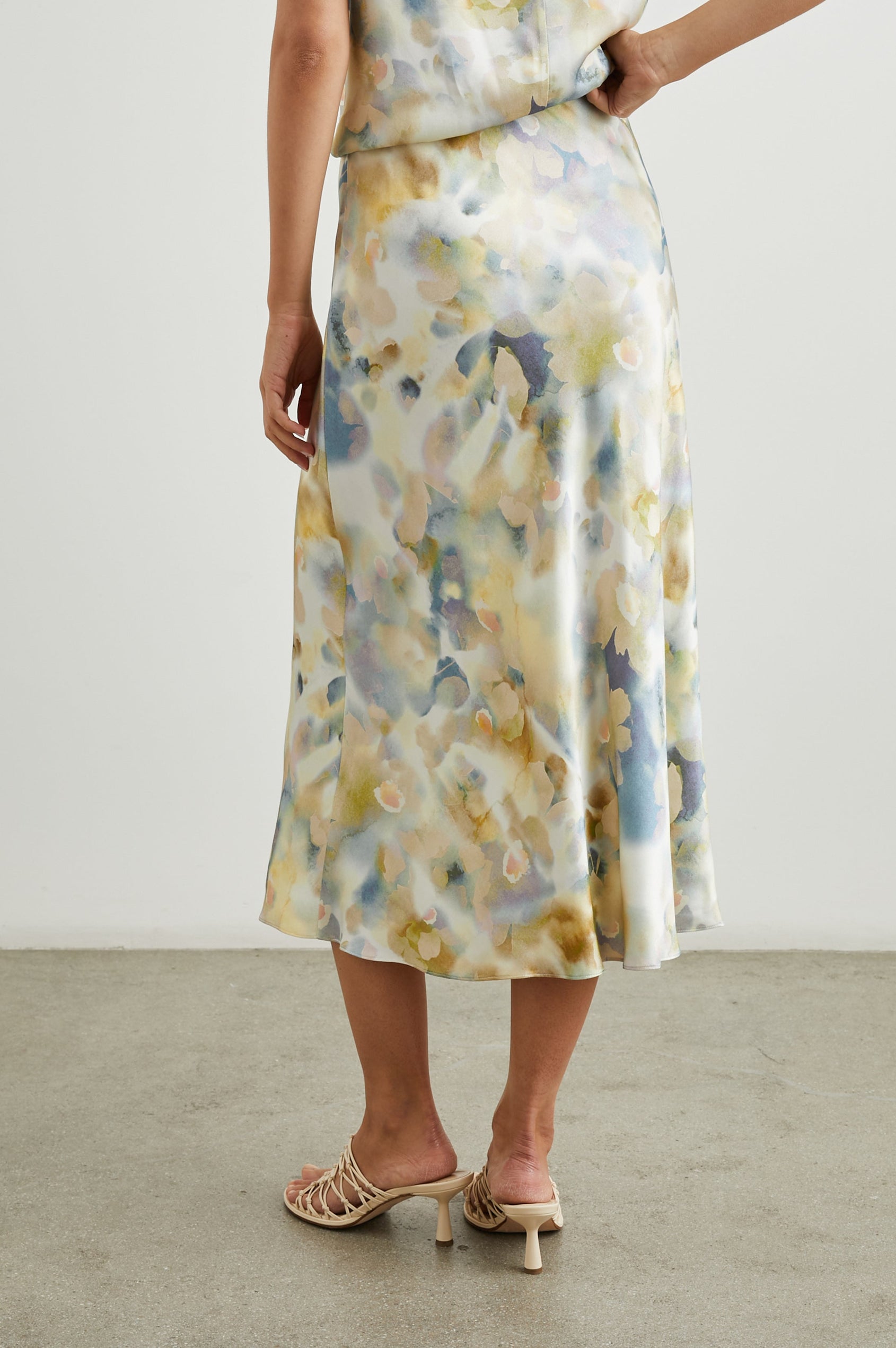 Anya High-waisted Midi Skirt in Diffused Blossom Colorway, with flowers in Creams, Golds and Blues on White - Back View Featured on Model