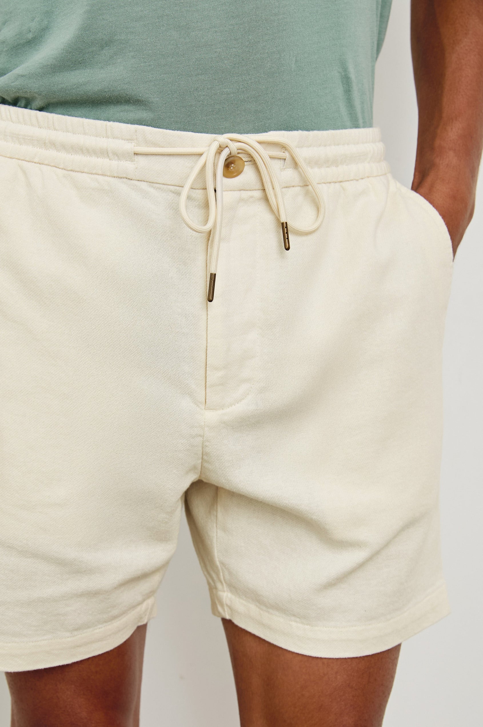 Archer medium length cotton short with adjustable drawstring and front button closure in Ecru - front view on model, hand in pocket