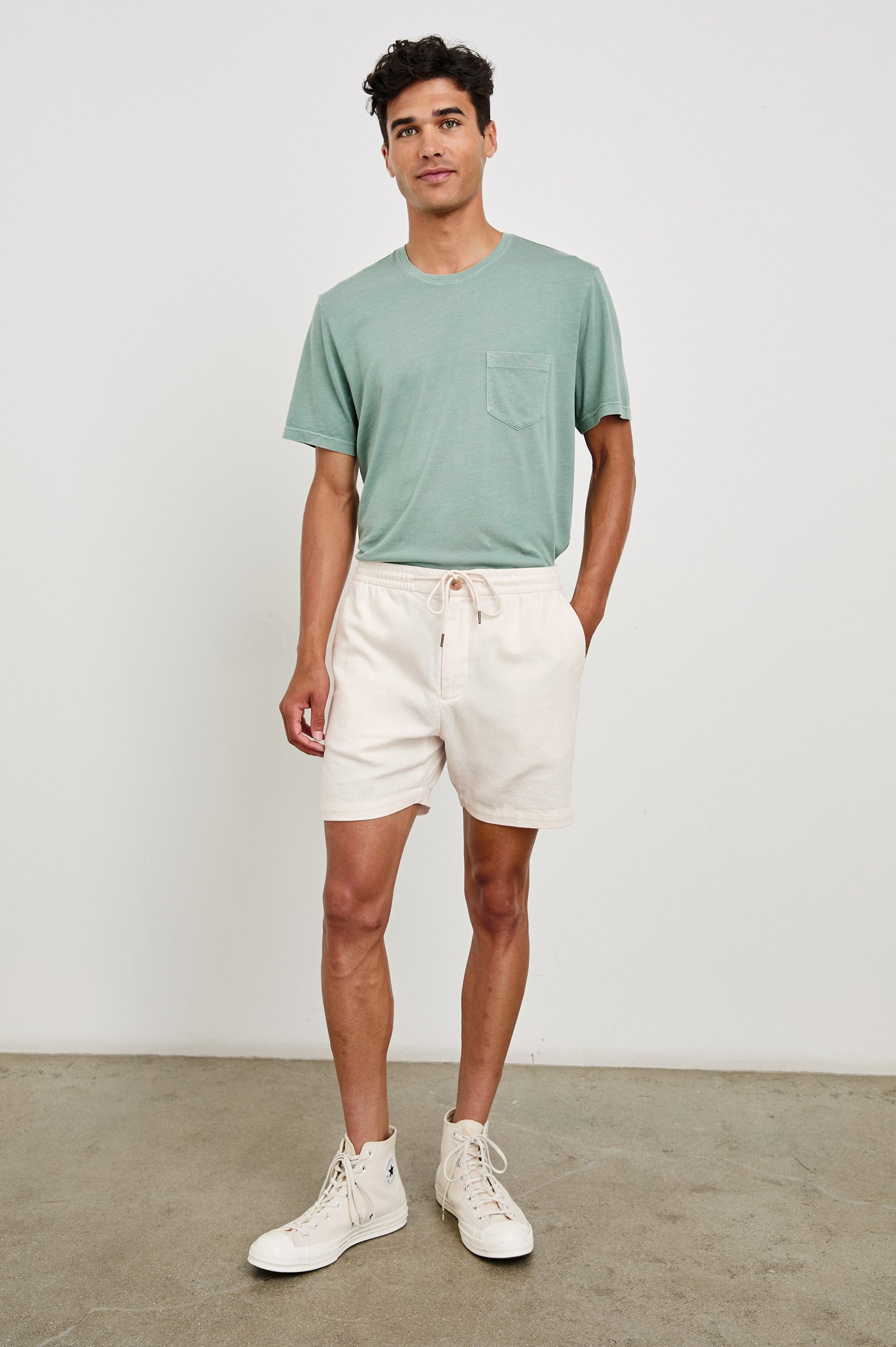 Archer medium length cotton short with adjustable drawstring and front button closure in Ecru - front view on model, hand in pocket