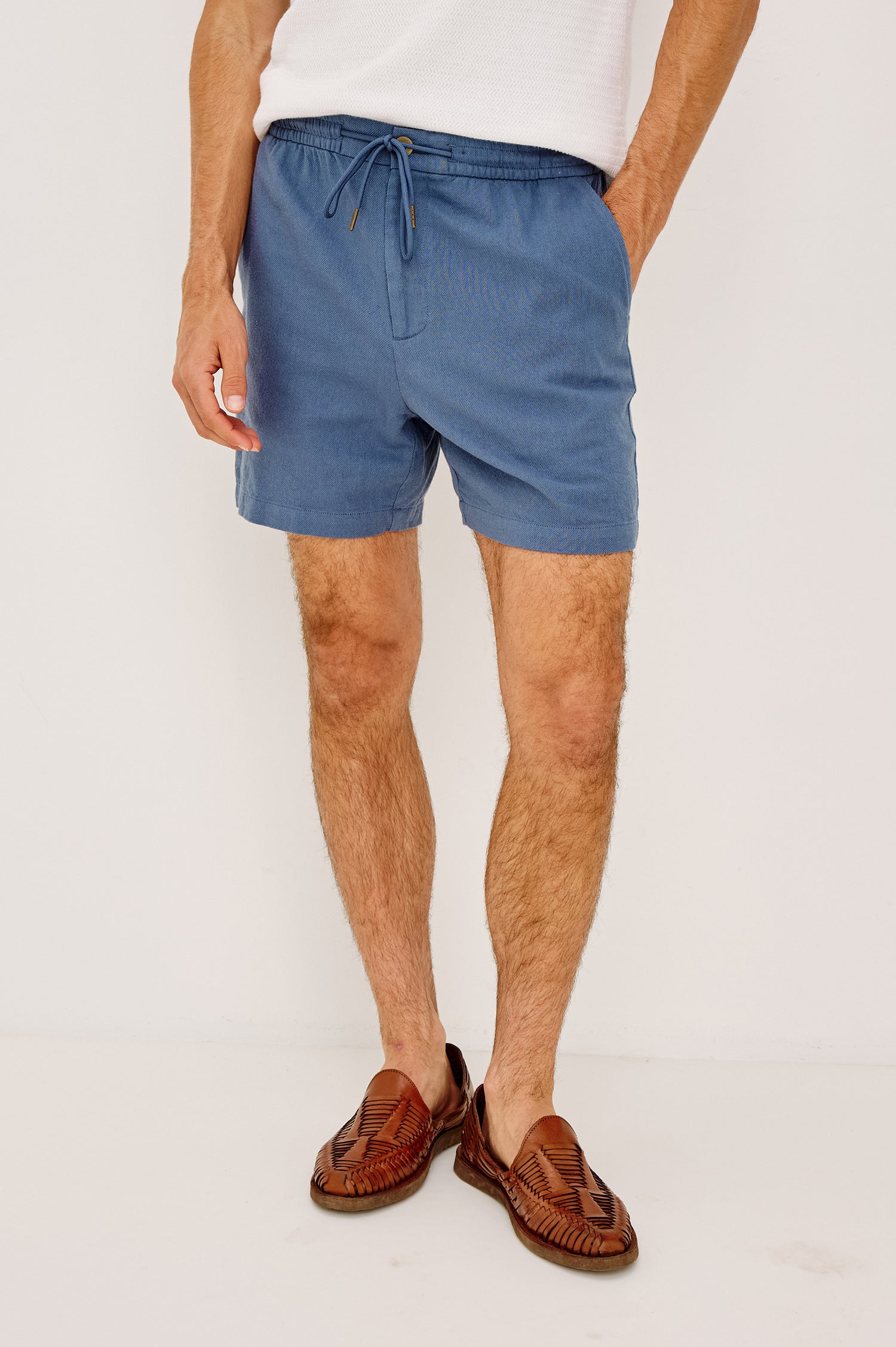 Archer Short in Heavy Linen With Relaxed Fit, Elastic Drawstring Waist, Front Zip Fly, 6″ Inseam, and Side Pockets in Washed Blue Colorway - Lower Body Front View Featured on Model