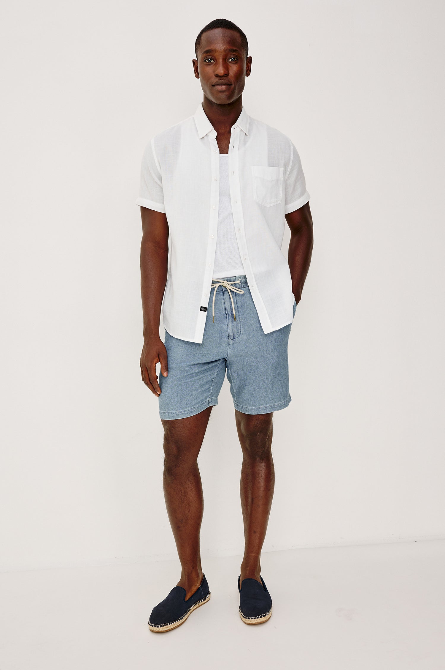 Archer Short in Unlined Cotton Linen With Relaxed Fit, Adjustable Waist Drawstring Ties, Side Pockts, and 8.5-Inch Inseam in Medium Wash Indigo Colorway - Full Body Front View Featured on Model