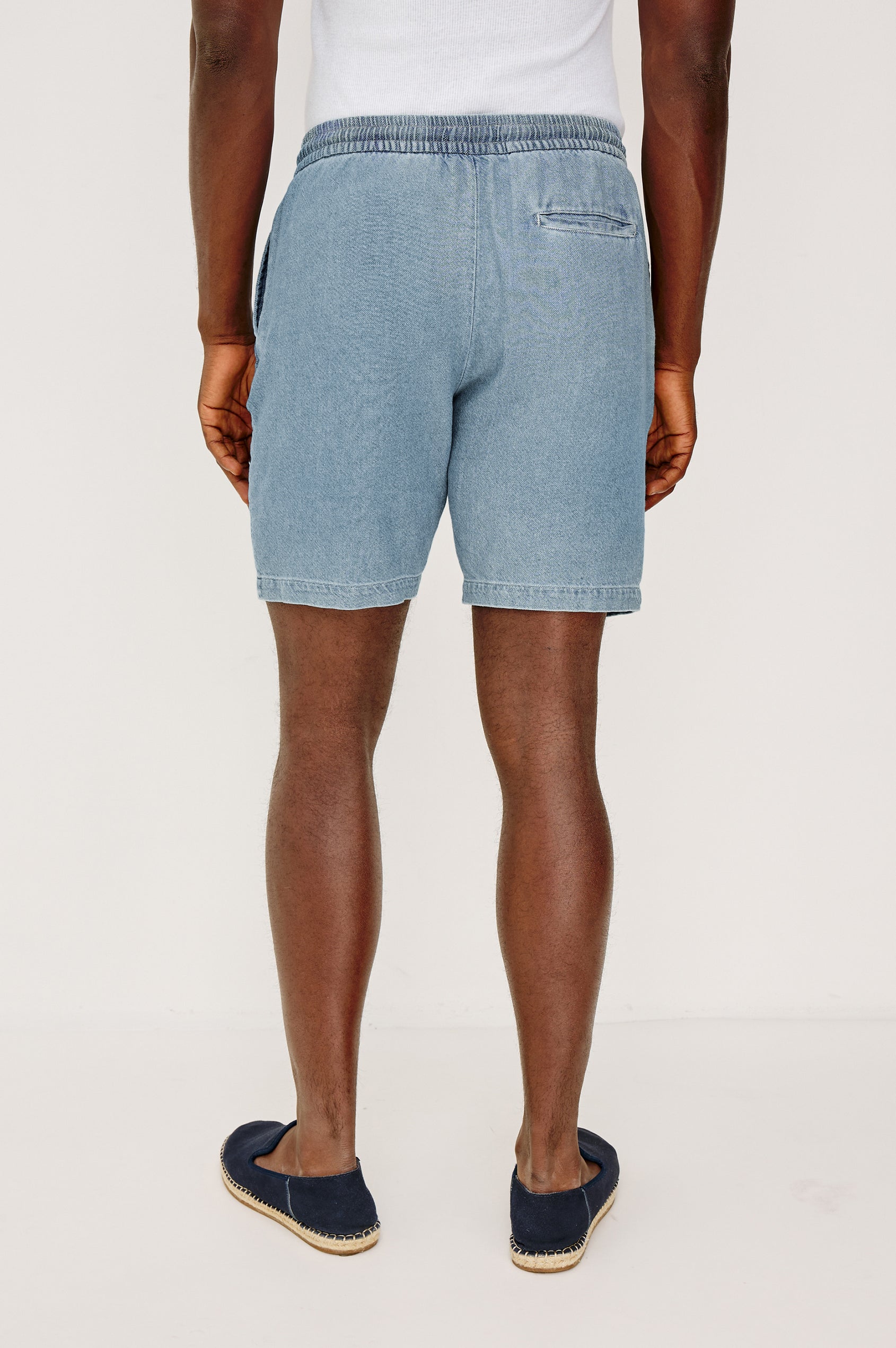 Archer Short in Unlined Cotton Linen With Relaxed Fit, Adjustable Waist Drawstring Ties, Side Pockts, and 8.5-Inch Inseam in Medium Wash Indigo Colorway - Lower Body Back View Featured on Model