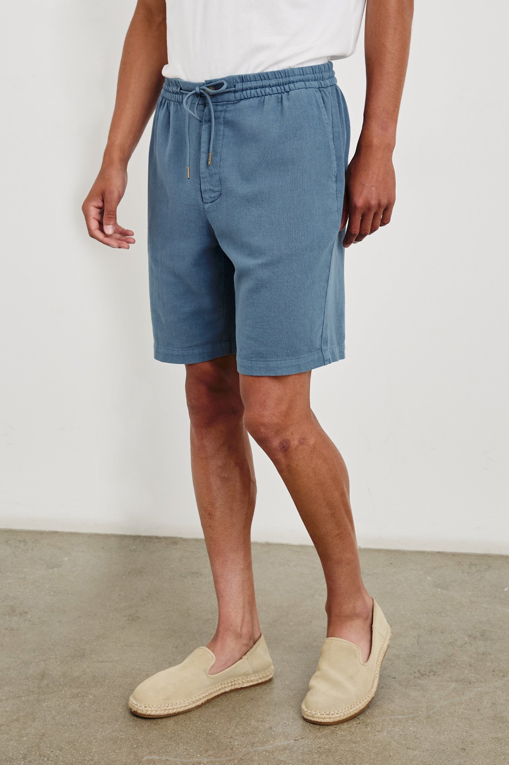 Archer long length cotton short with adjustable drawstring and front button closure in Washed Blue - front view on model, slight angle in motion.