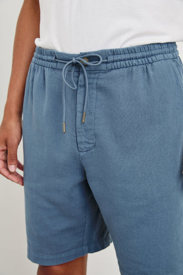 Archer long length cotton short with adjustable drawstring and front button closure in Washed Blue - front view on model