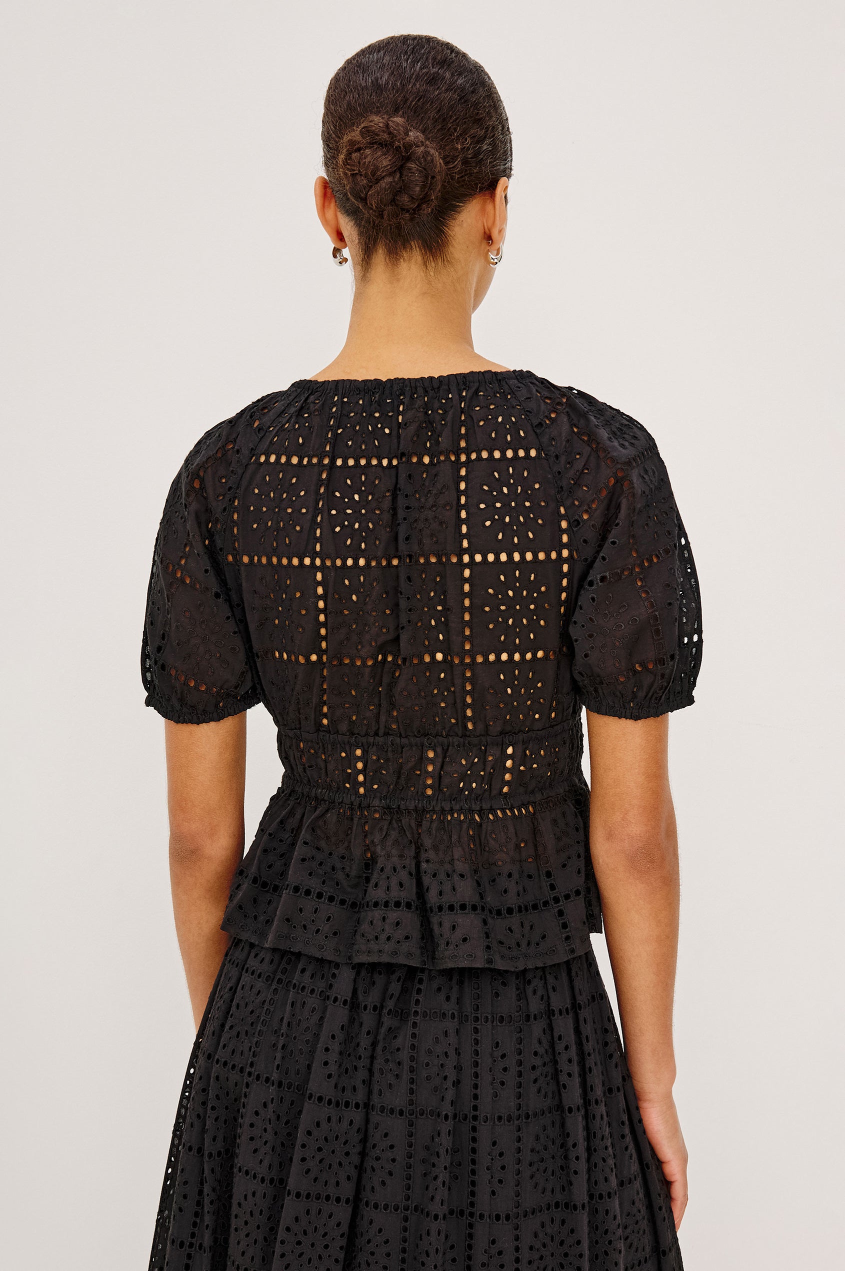 Argenta Top in Cotton Voile With Embroidered Pattern, Short Puff Sleeves, Hook-and-Eye Closure, Elastic V-Neckline and Waist, and Peplum Hem in Black Grid Embroidery Colorway - Upper Body Back View Featured on Model