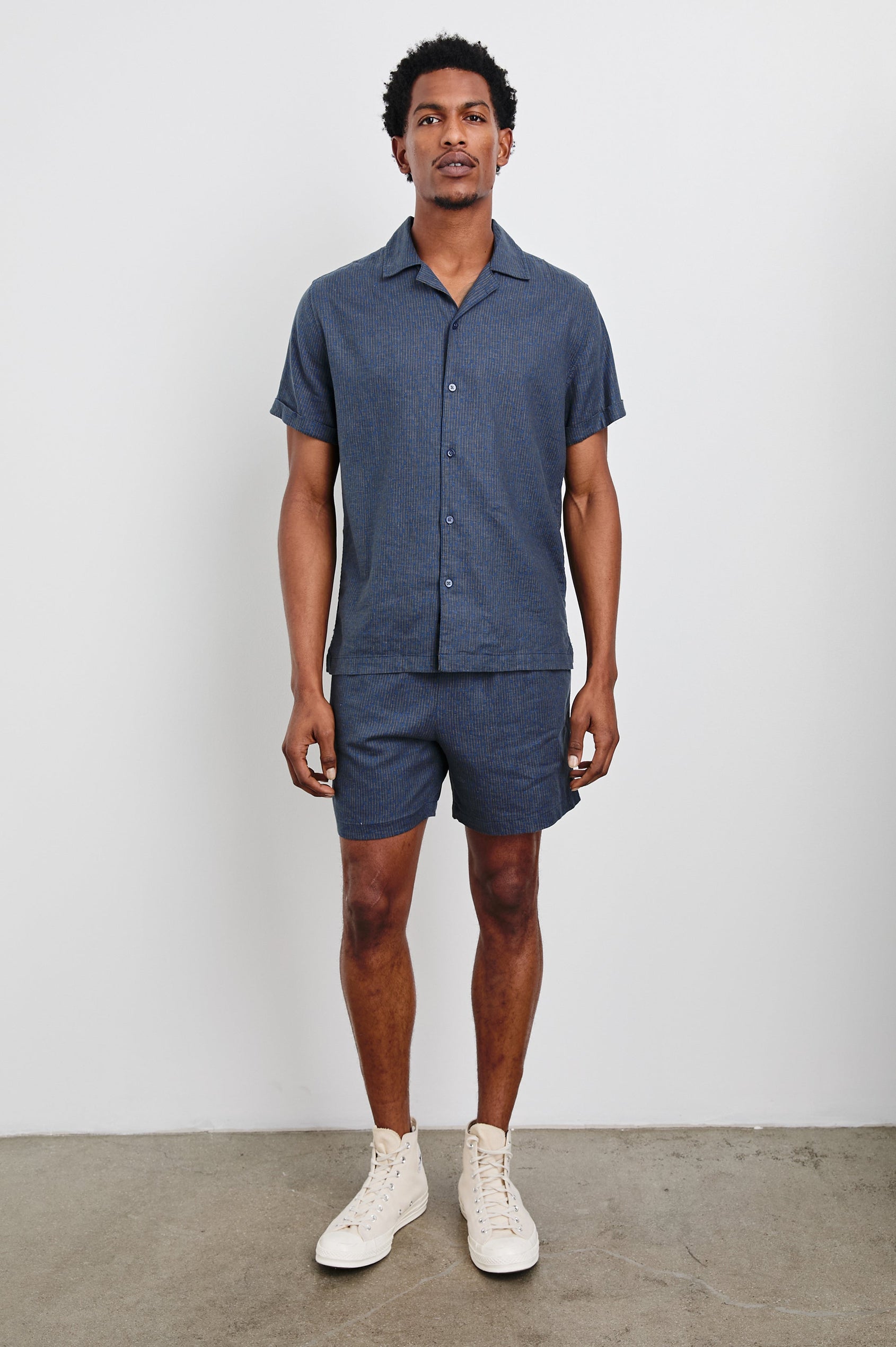 Aries Shorts with a Drawstring Waist, Two Front Pockets and a Buttoned Back Patch Pocket in Navy Cedar Vertical Colorway, with Thin Vertical Cedar Dashes on Navy - Front Full Body View Featured on Model