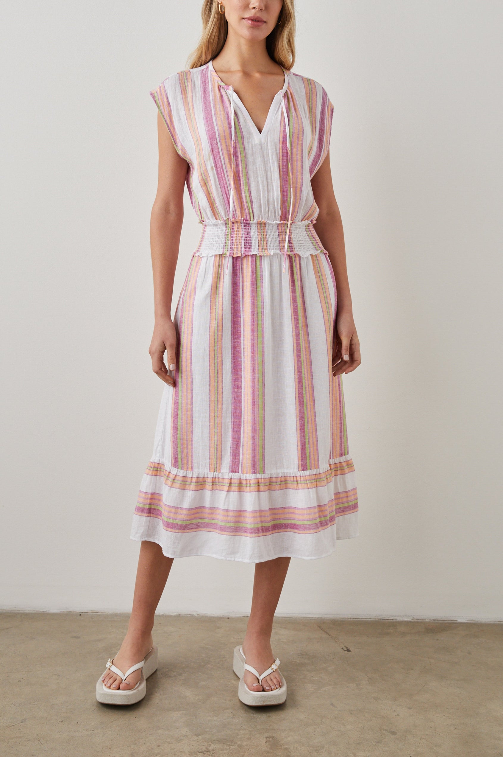 Ashlyn Short Sleeve Midi Dress with a V neck with Ties, a Smocked Waist and a Ruffle Tier at the Hem in Hibiscus Stripe Colorway, Vertical Stripes in Pink, Green and Peach on White - Front Full Body View Featured on Model