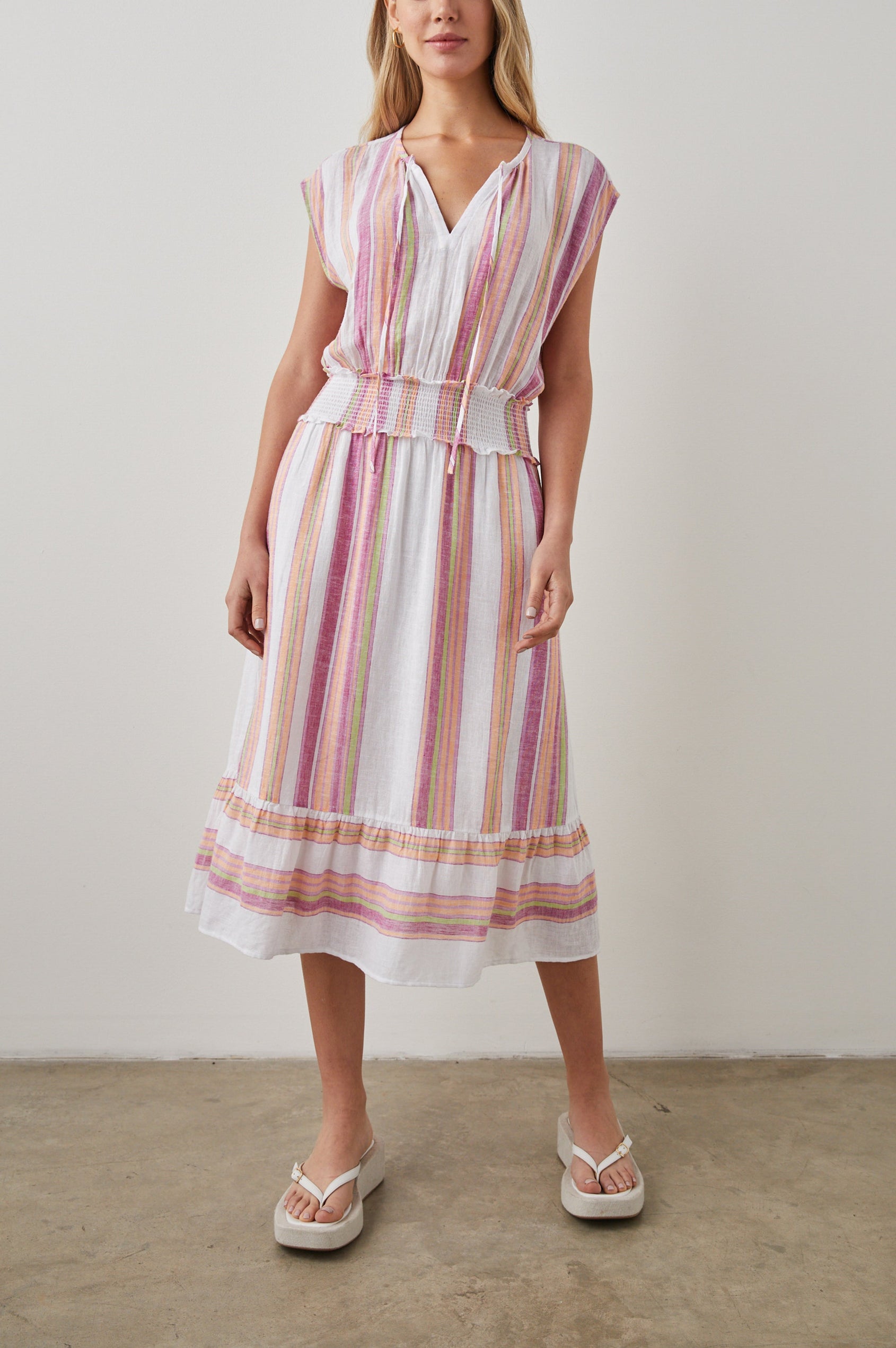 Ashlyn Short Sleeve Midi Dress with a V neck with Ties, a Smocked Waist and a Ruffle Tier at the Hem in Hibiscus Stripe Colorway, Vertical Stripes in Pink, Green and Peach on White - Front Full Body View Featured on Model