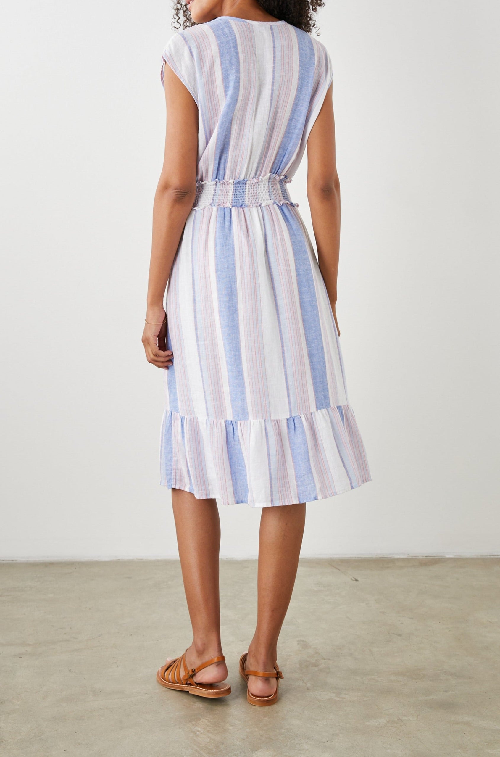 Ashlyn Short Sleeve Midi Dress with a V neck with Ties, a Smocked Waist and a Ruffle Tier at the Hem in Marini Stripe Colorway, Vertical Stripes in Pink and Blue on White - Back Full Body View Featured on Model