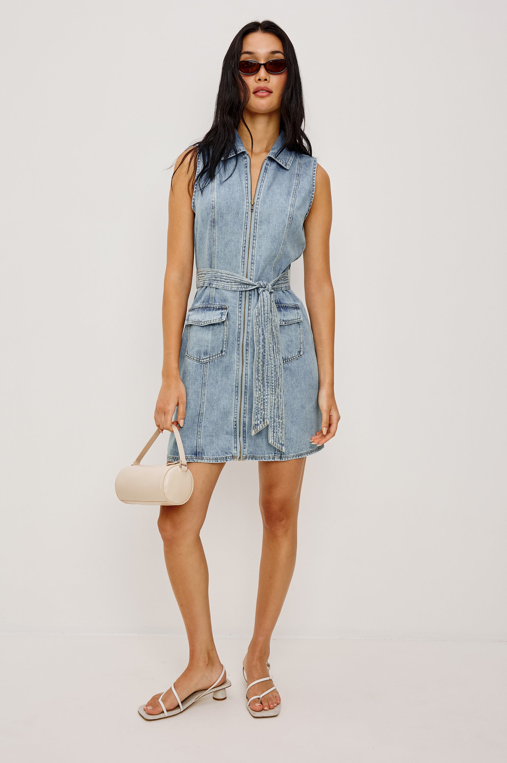 Aurora Sleeveless Mini Dress in TENCELâ„¢Denim With Collar Front Exposed Zipper Adjustable Belted Ties Side Flap Pockets in Faded Indigo Colorway - Full Body Front View Featured on Model