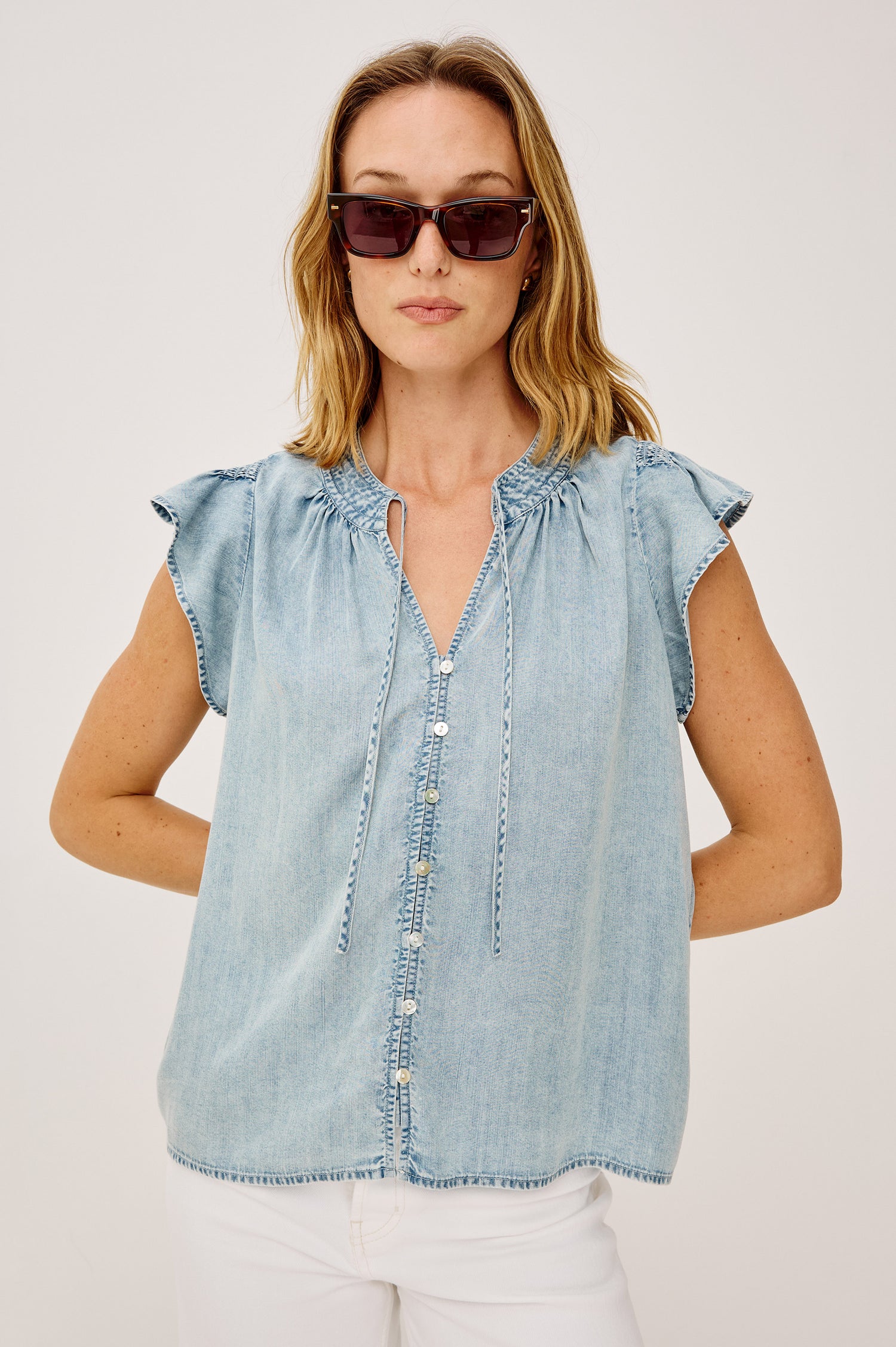 Aviva Top in TENCEL™ Denim With Smocked Flutter Sleeves, Split V-Neck With Embroidered Collar and Self-Ties, and Front Buttons in Bleached Indigo Colorway - Upper Body Front View Featured on Model