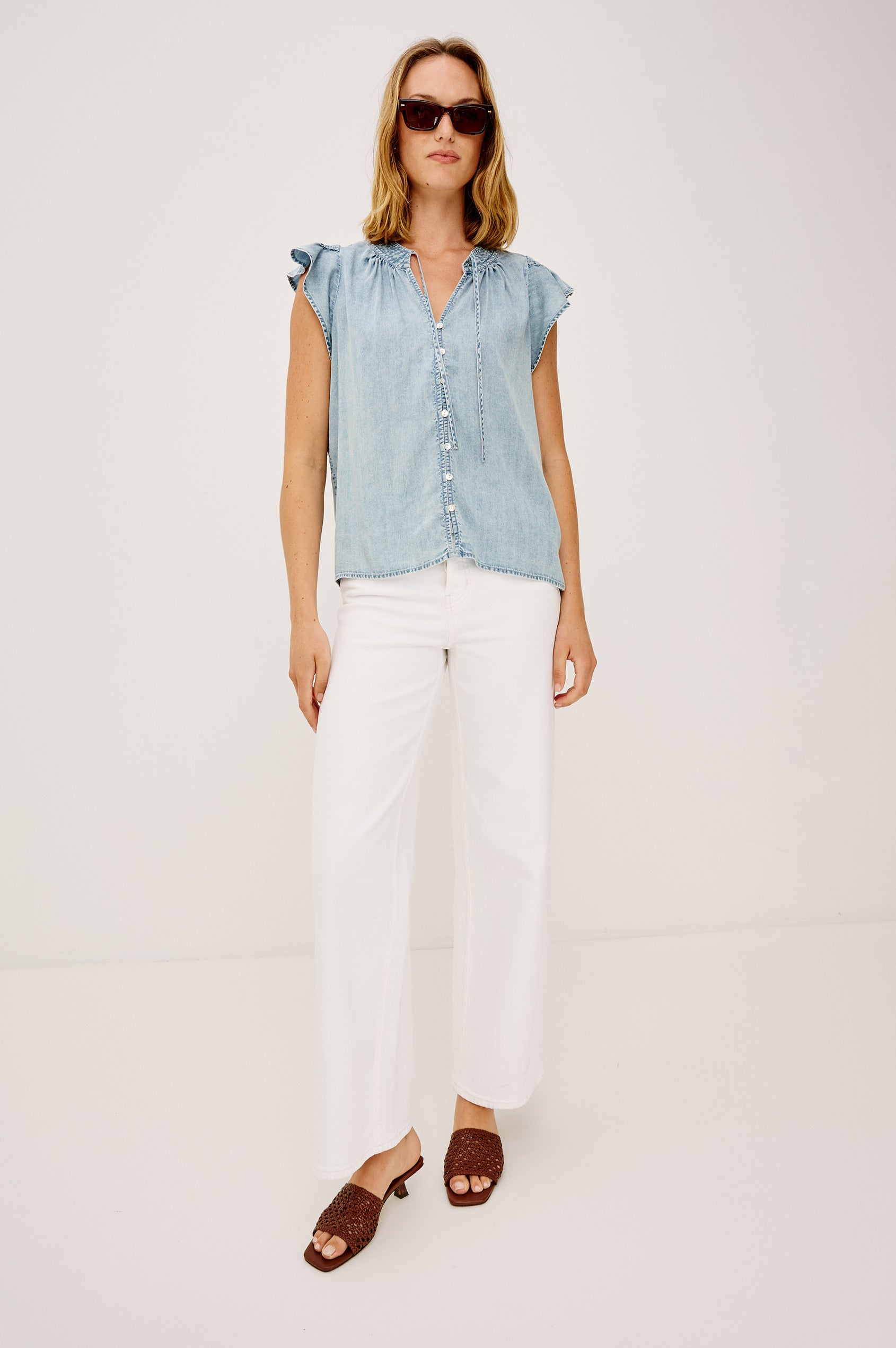 Aviva Top in TENCELT Denim With Smocked Flutter Sleeves, Split V-Neck With Embroidered Collar and Self-Ties, and Front Buttons in Bleached Indigo Colorway - Upper Body Front View Featured on Model