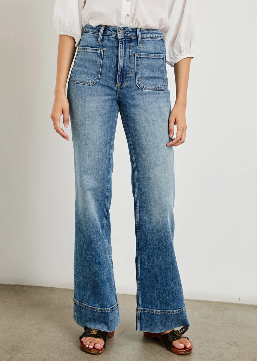 Person wearing blue jeans with a plain background