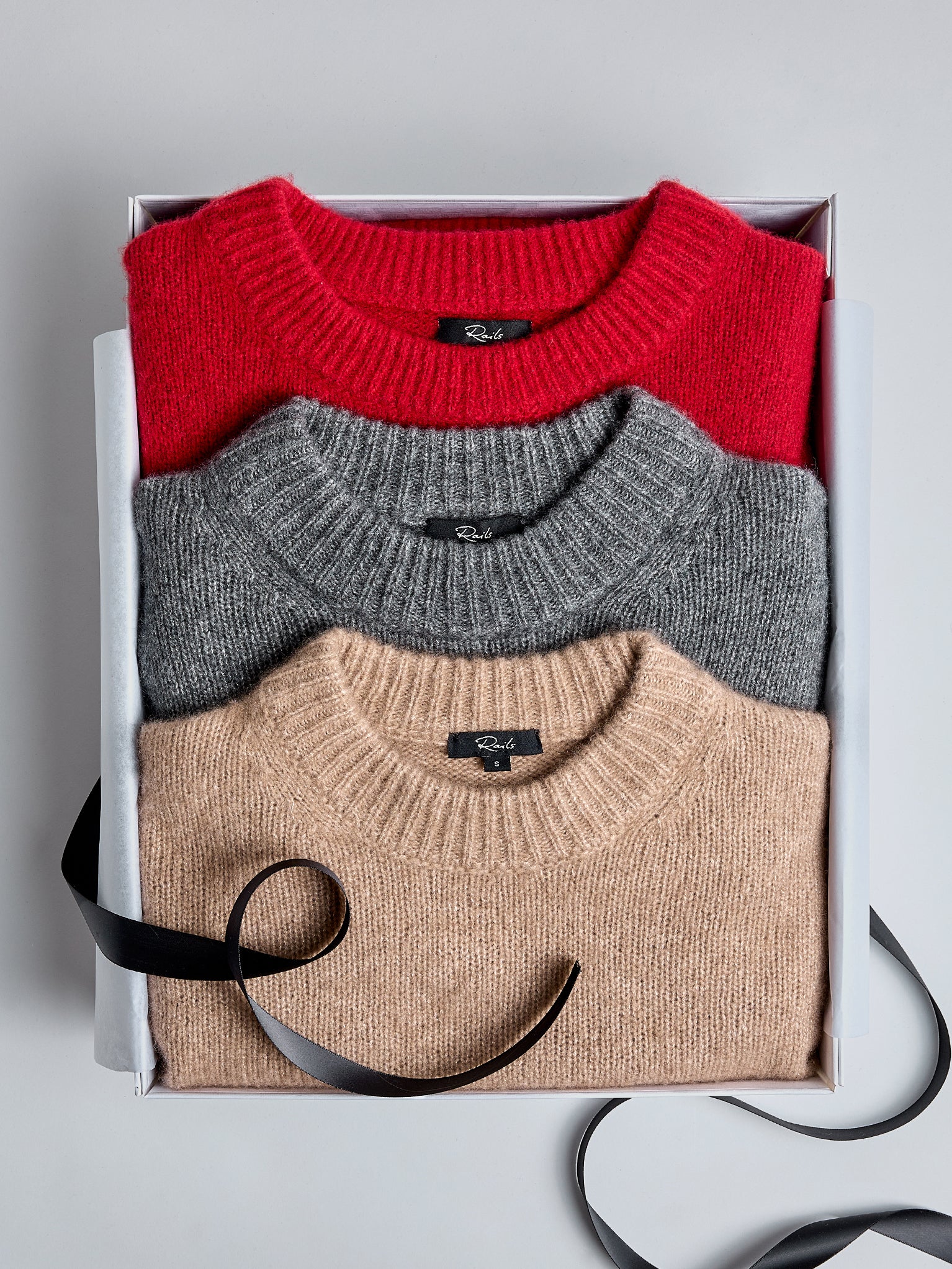 EDITORIAL IMAGE OF MULTIPLE CASHMERE SWEATERS FOLDED IN A GIFT BOX