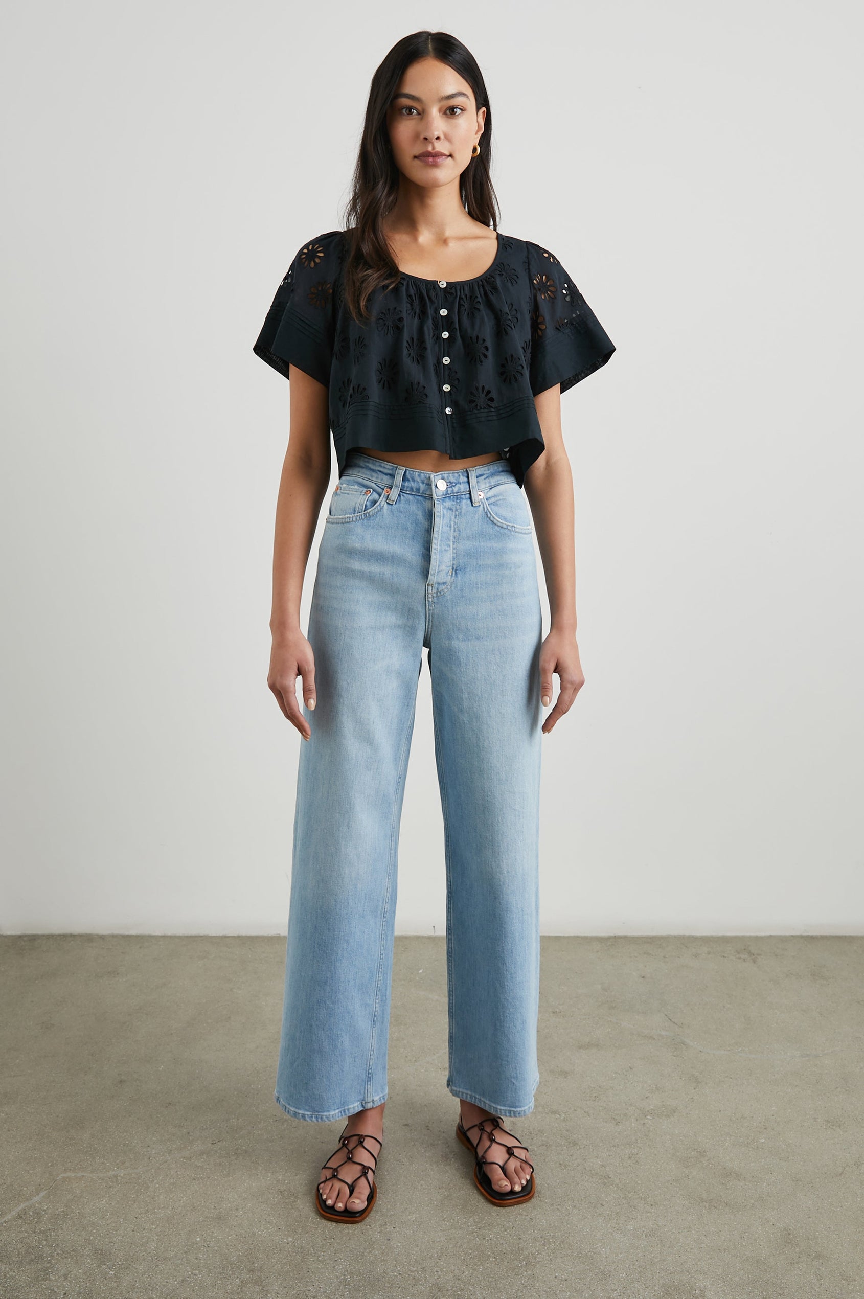 Bambina Short-Sleeve Cropped Top with a Scoop Neck, Buttons Down the Front, and Floral Eyelets in Black Colorway - Front Full Body View Featured on Model 
