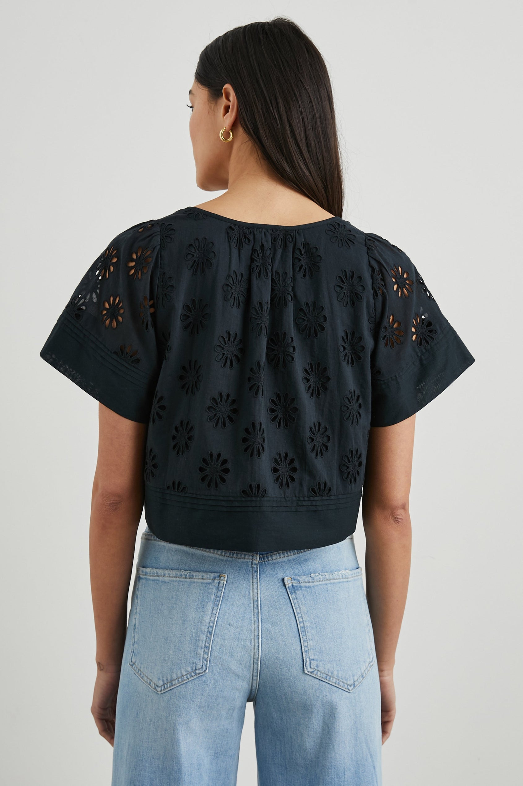 Bambina Short-Sleeve Cropped Top with a Scoop Neck, Buttons Down the Front, and Floral Eyelets in Black Colorway - Back View Featured on Model 