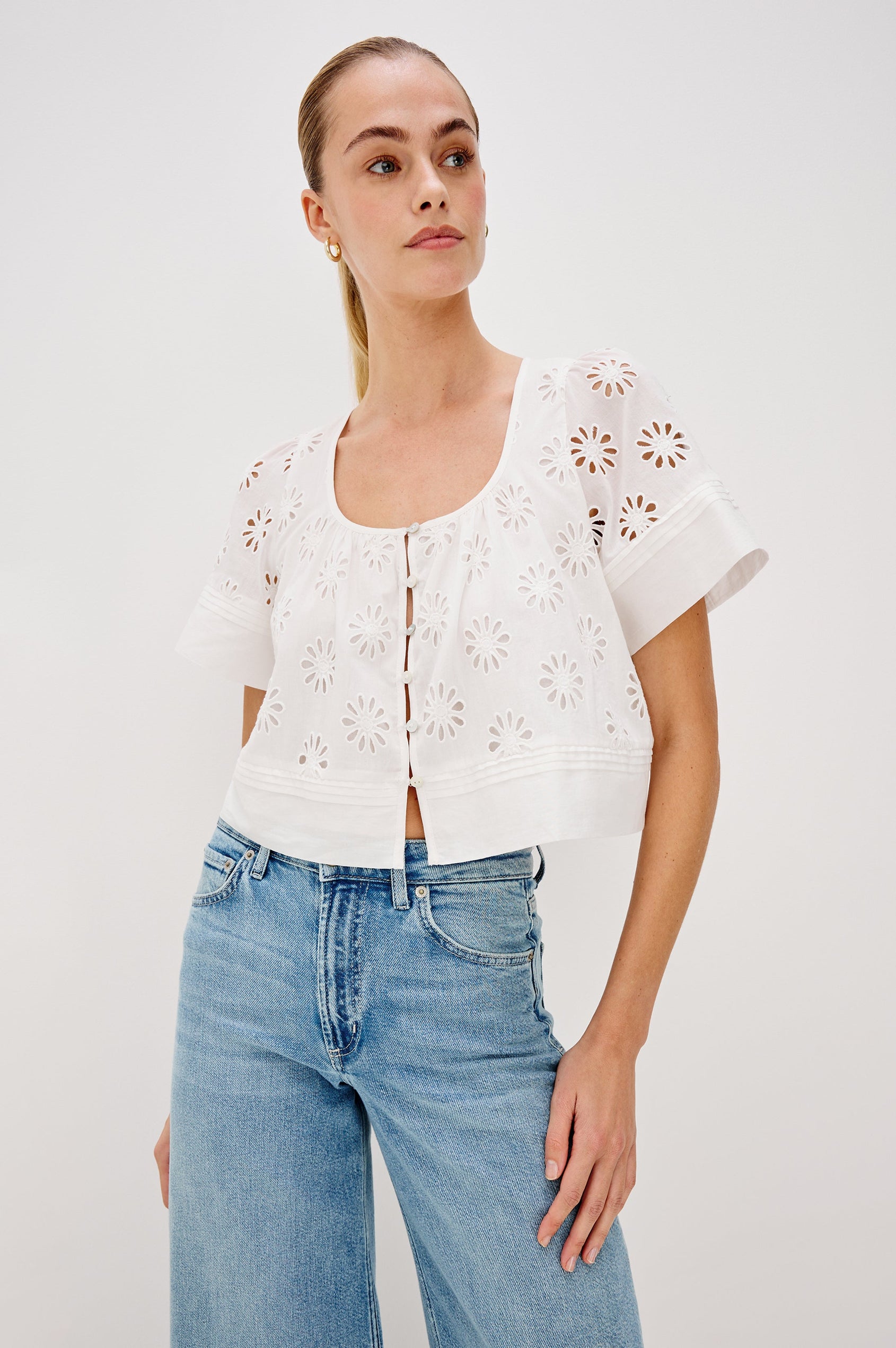 Bambina scoop neck top with short sleeves, button front, baby doll shape with cutout flowers through out in White colorway. Front View Shown on Model.