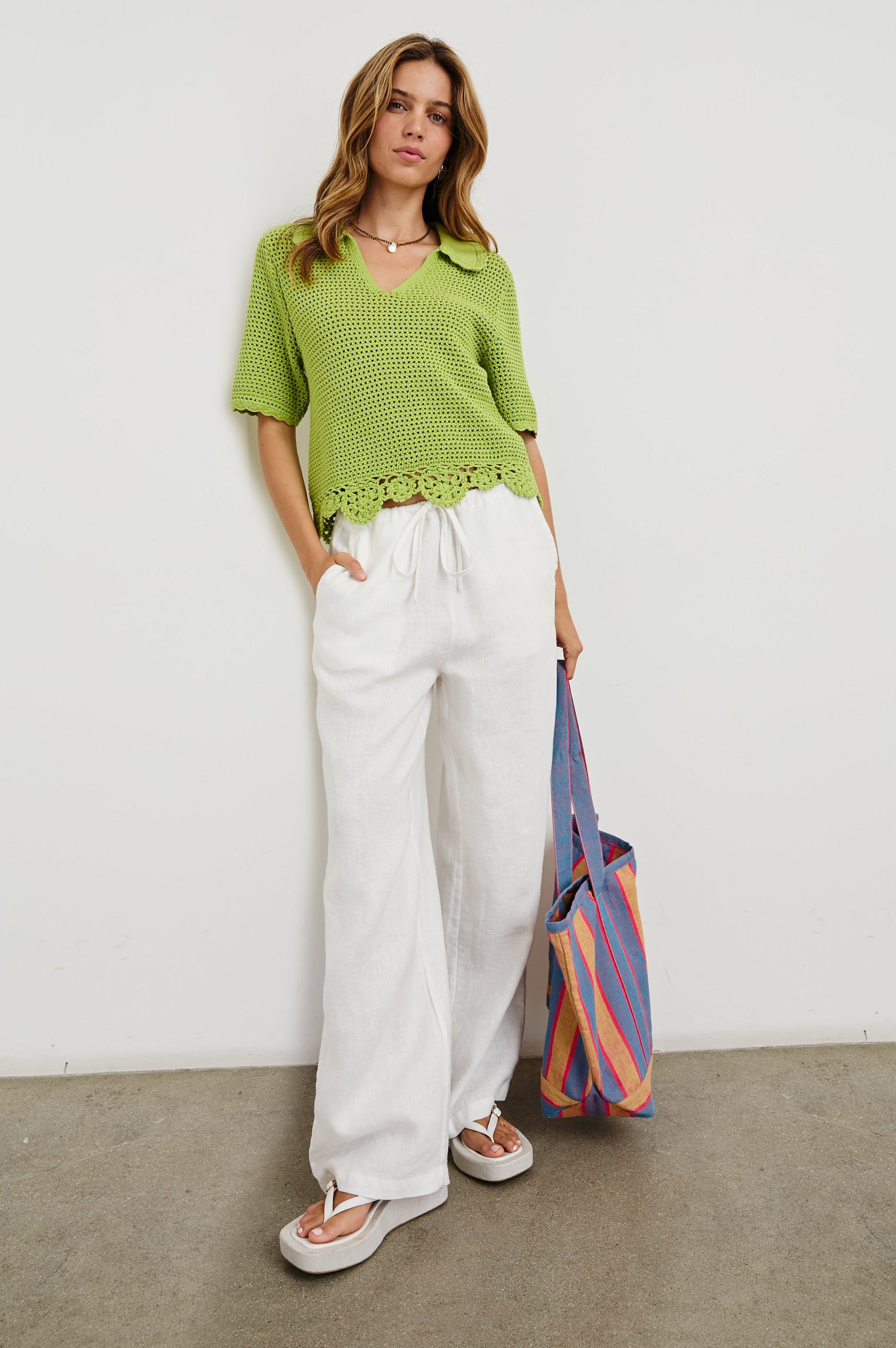 Striped linen Beach Tote with front pocket and long, wide shoulder straps in Rio Stripe - full body front view of model, holding bag at side