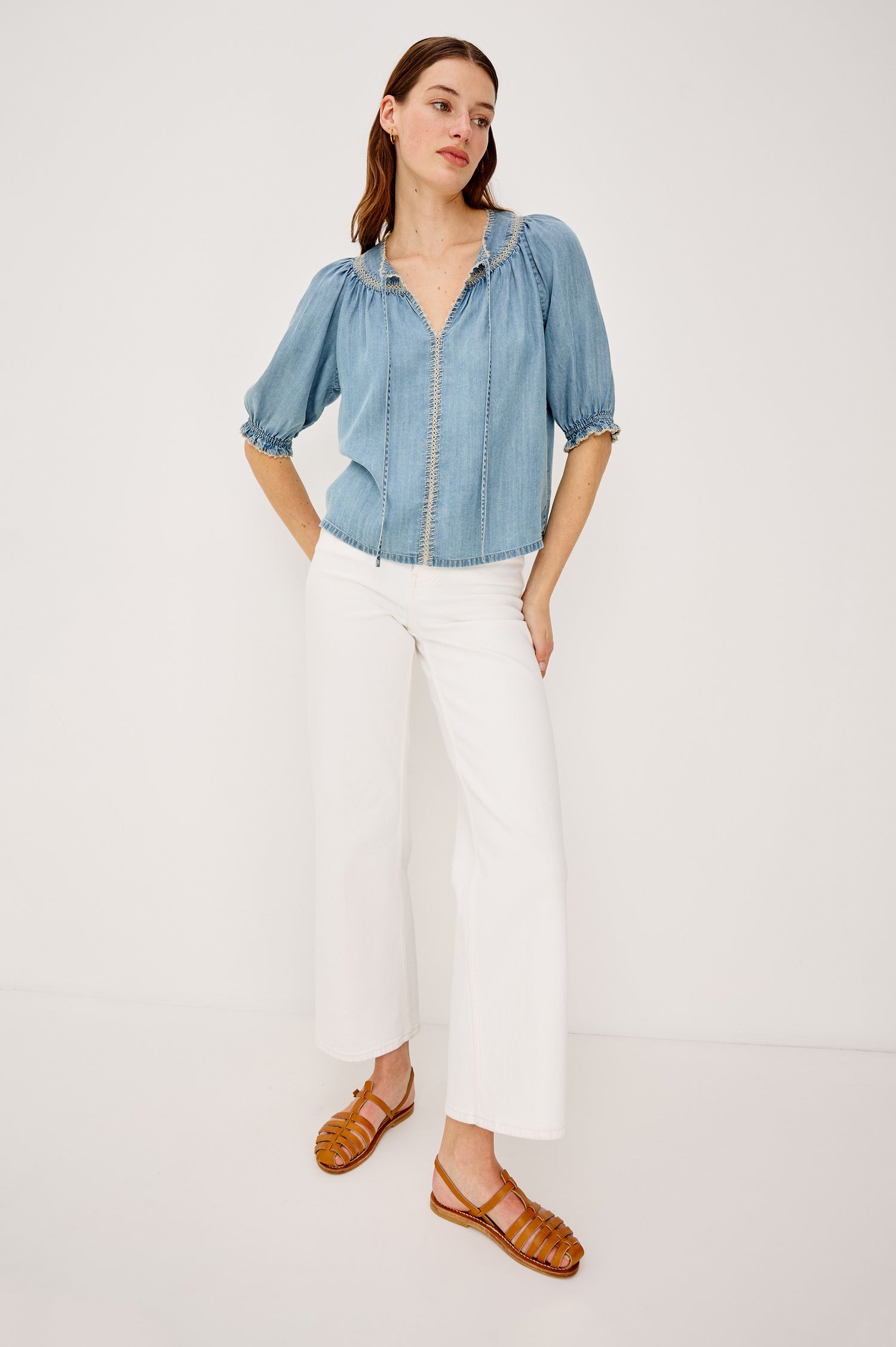 Belina Peasant Top in TENCELâ„¢ Denim With Gathered V-Neckline With Self Ties Blanket Stitch Embroidered Trim Loose Fit and Elbow-Length Puff Sleeves With Elastic Cuffs - Full Body Front View Featured on Model