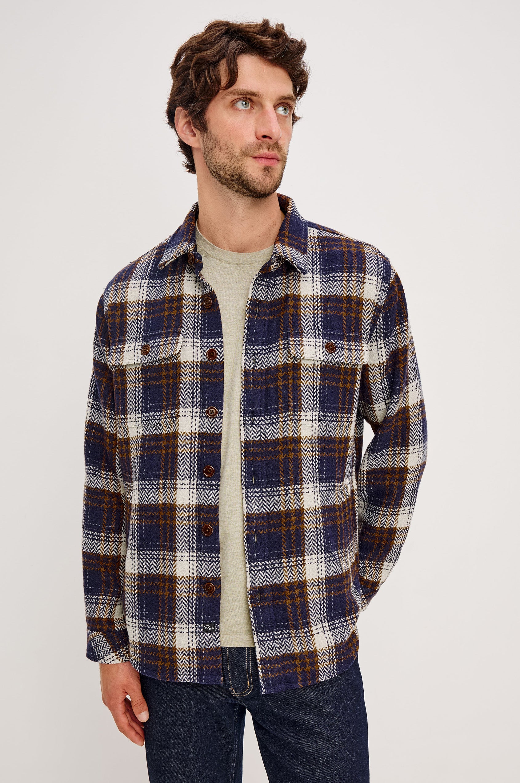 The Berkshire is a plaid shirt jacket with two chest pockets button front and collar in Navy Umber Cream colorway. Front view featured on model.