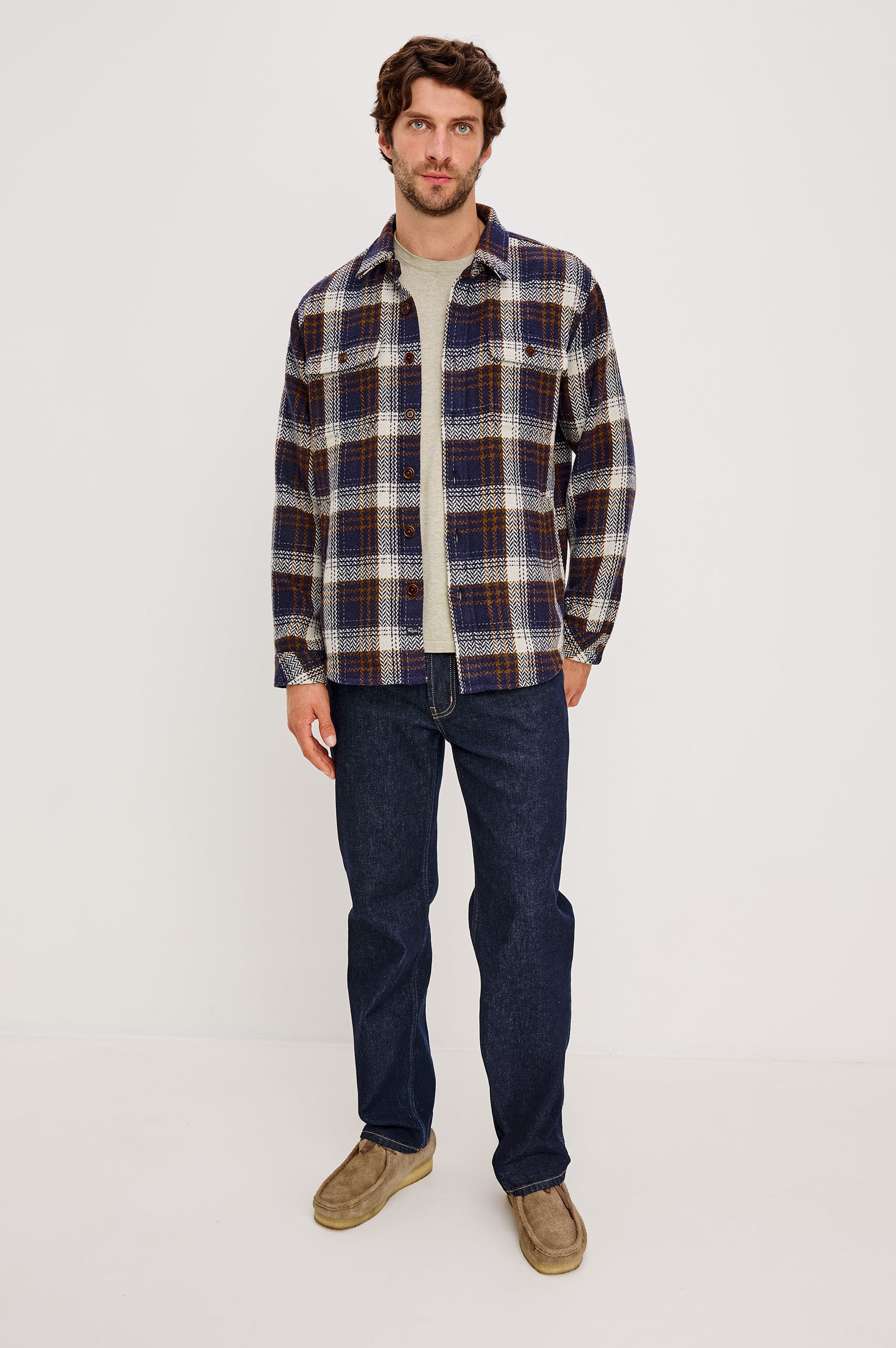 The Berkshire is a plaid shirt jacket with two chest pockets button front and collar in Navy Umber Cream colorway. Front full body view featured on model.